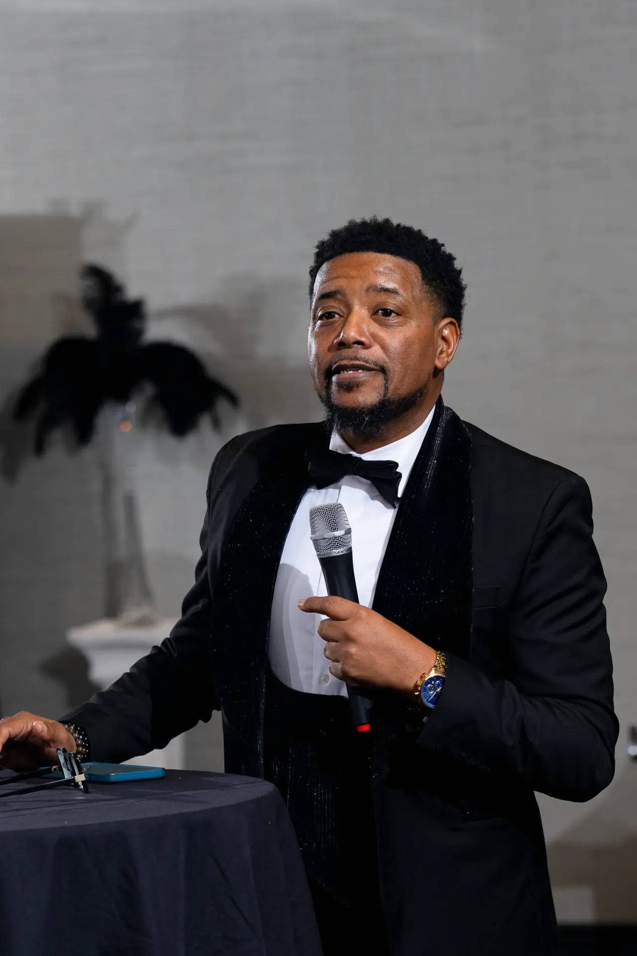 Emcee in a tuxedo speaking into a microphone at a gala