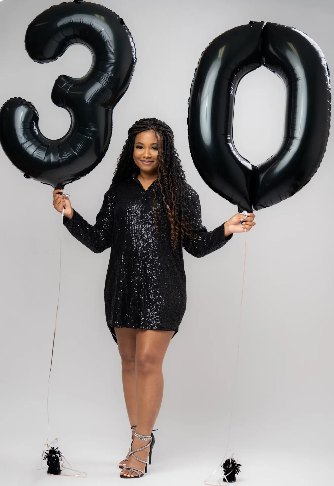 Woman holding black "30" number balloons