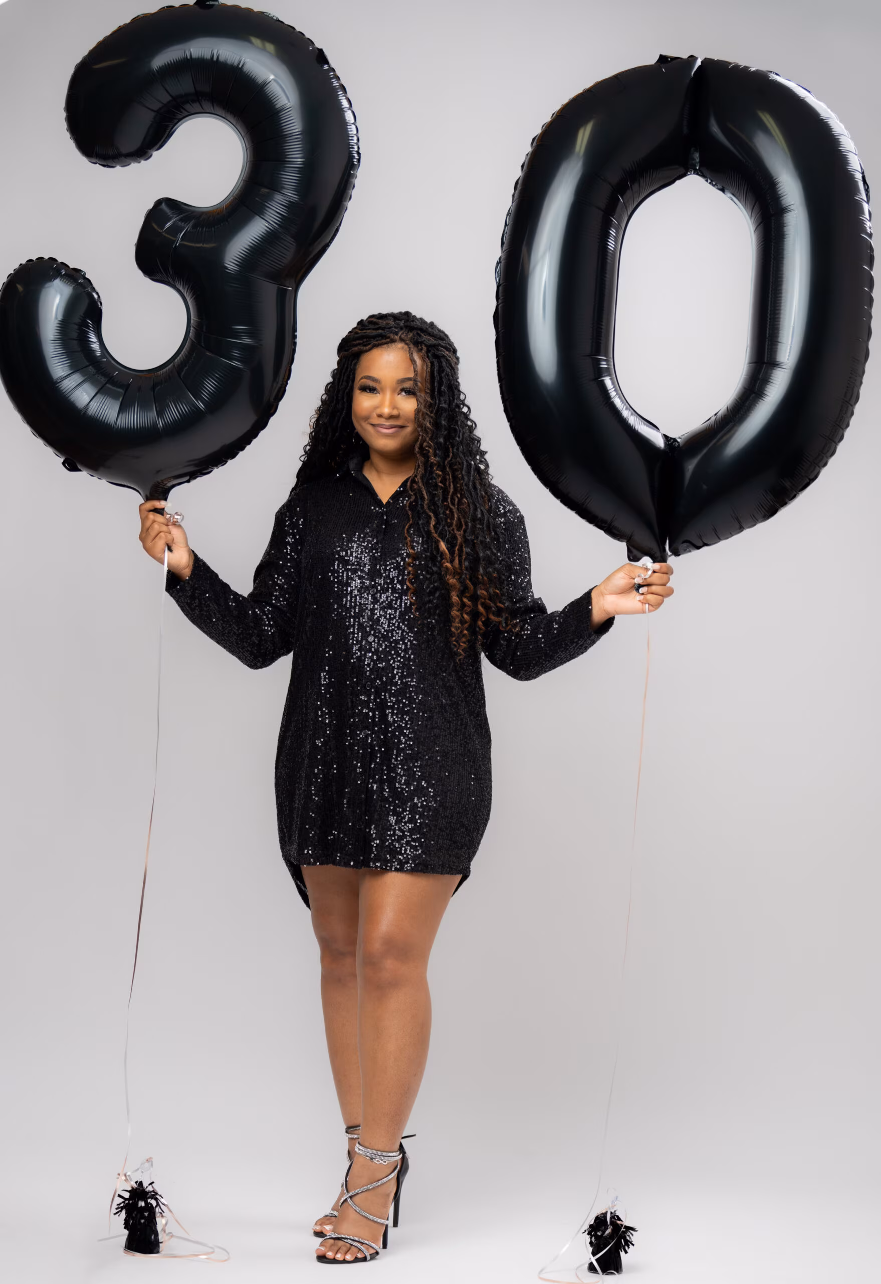 Woman holding black "30" number balloons