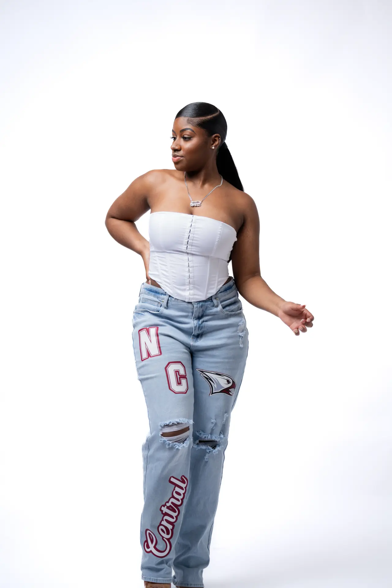 Model in a white top and patterned jeans posing on a white backdrop
