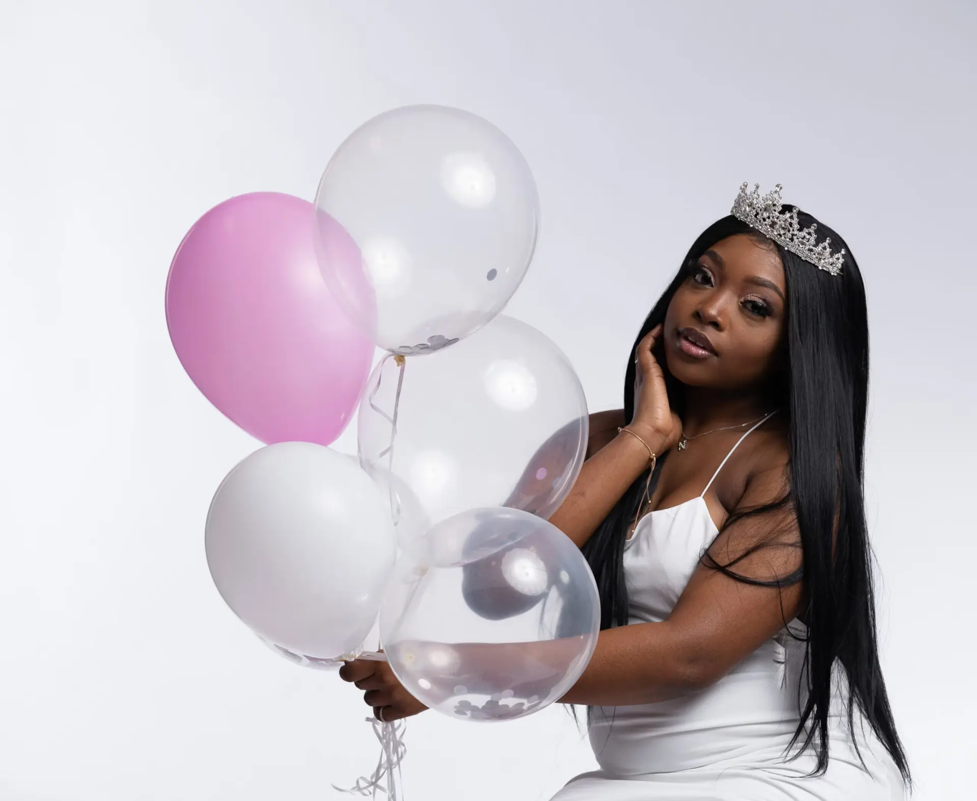 Woman in a tiara holding pink and white balloons
