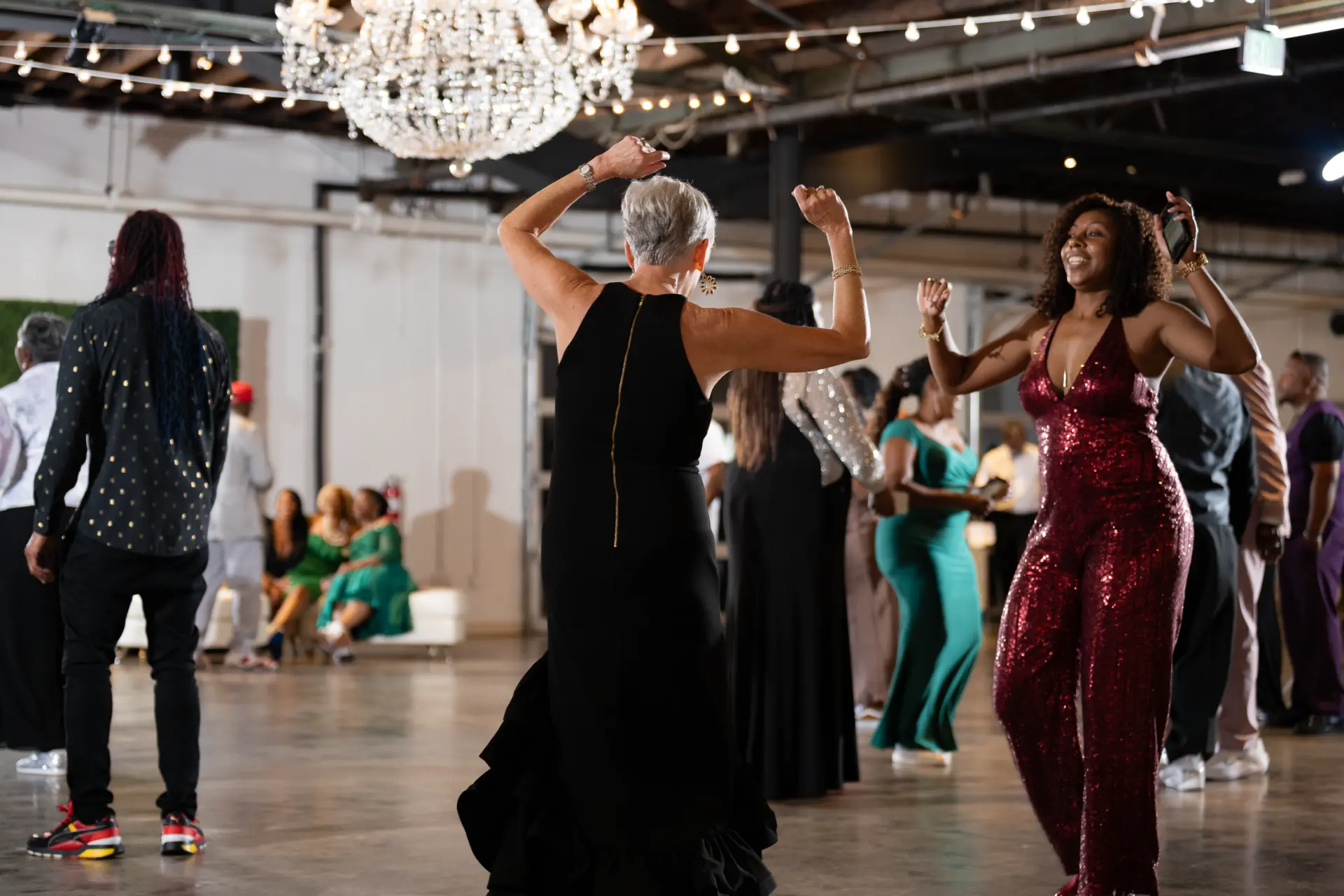 Guests dancing in a line under chandeliers at a reception