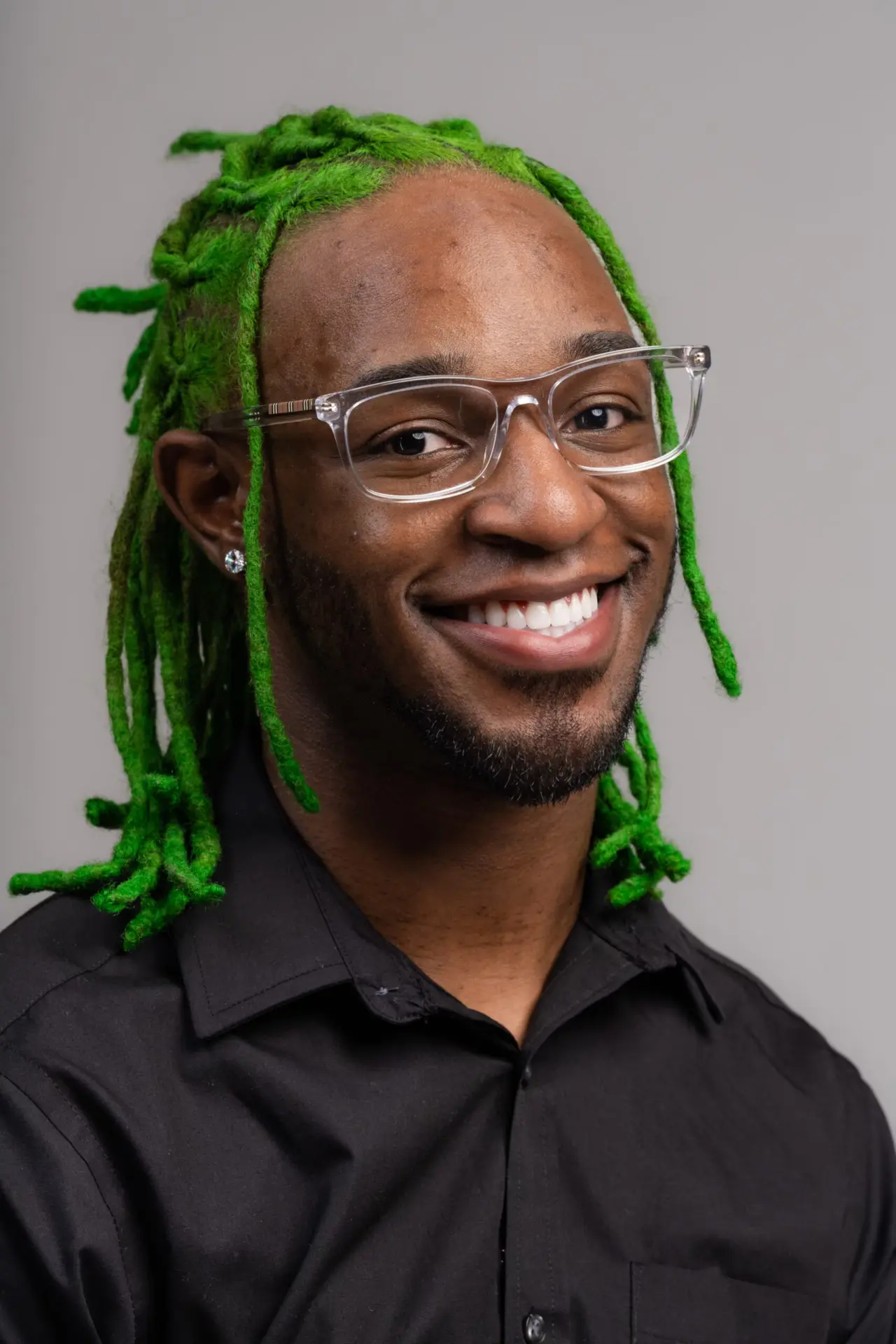 Smiling man with green locs and glasses, birthday portrait