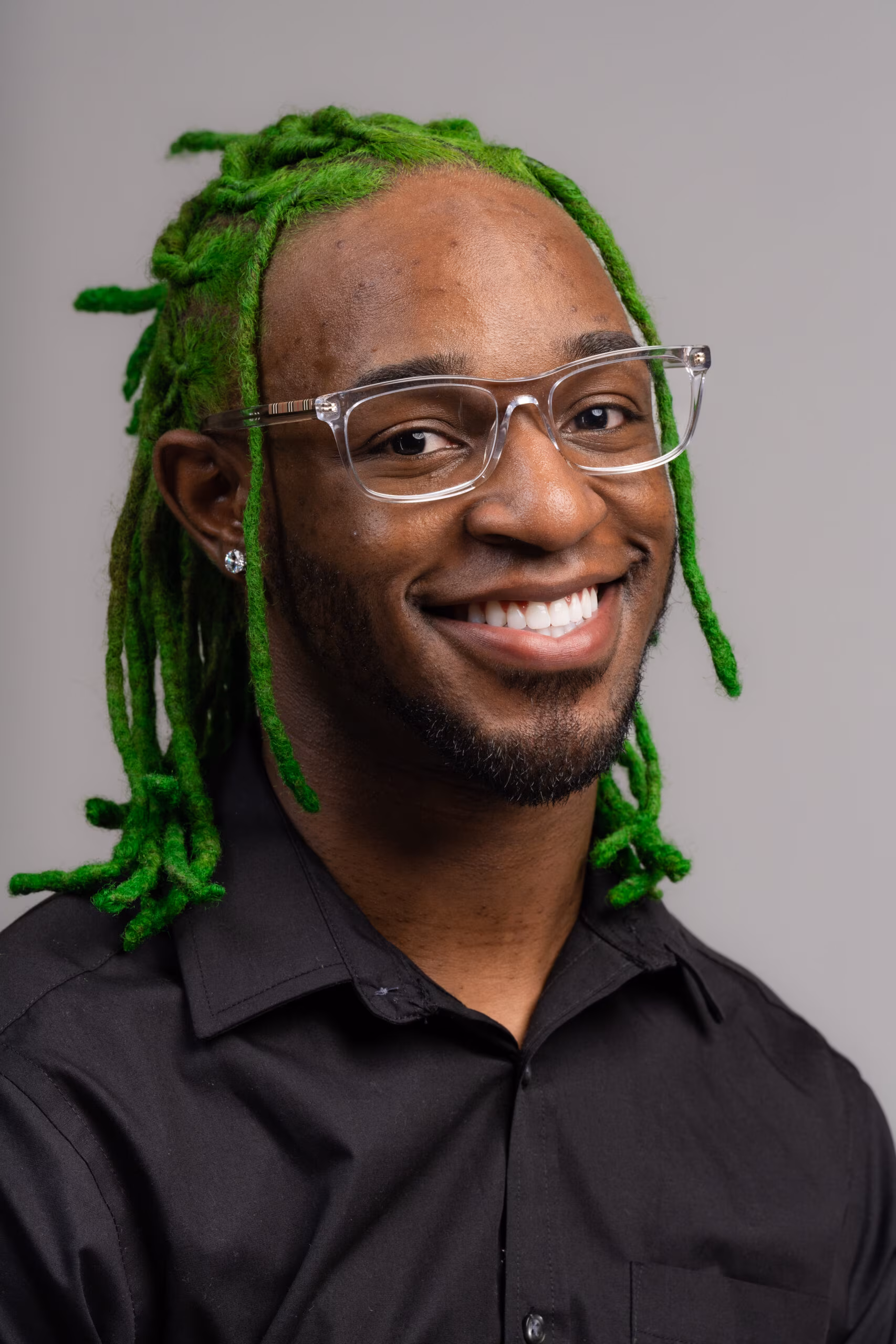 Smiling man with green locs and glasses, birthday portrait