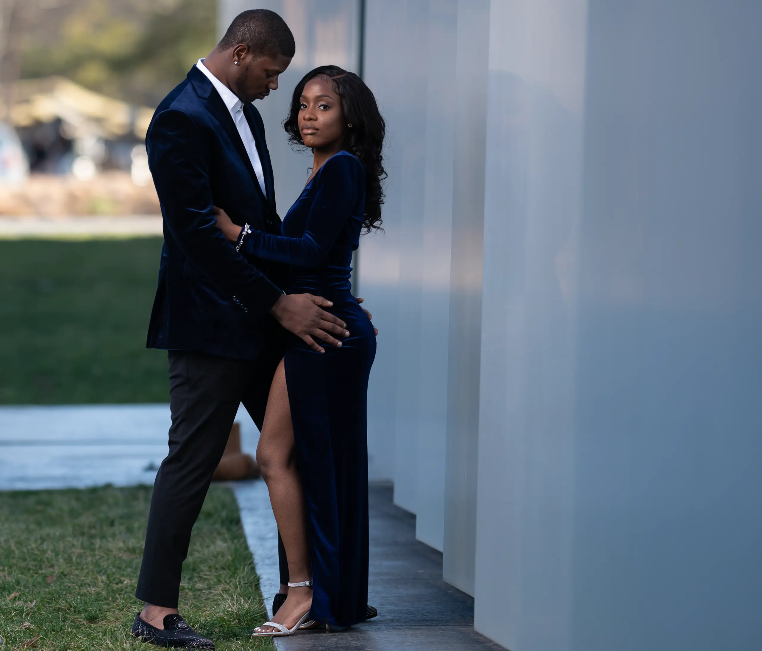 Couple in black outfits leans close beside white columns