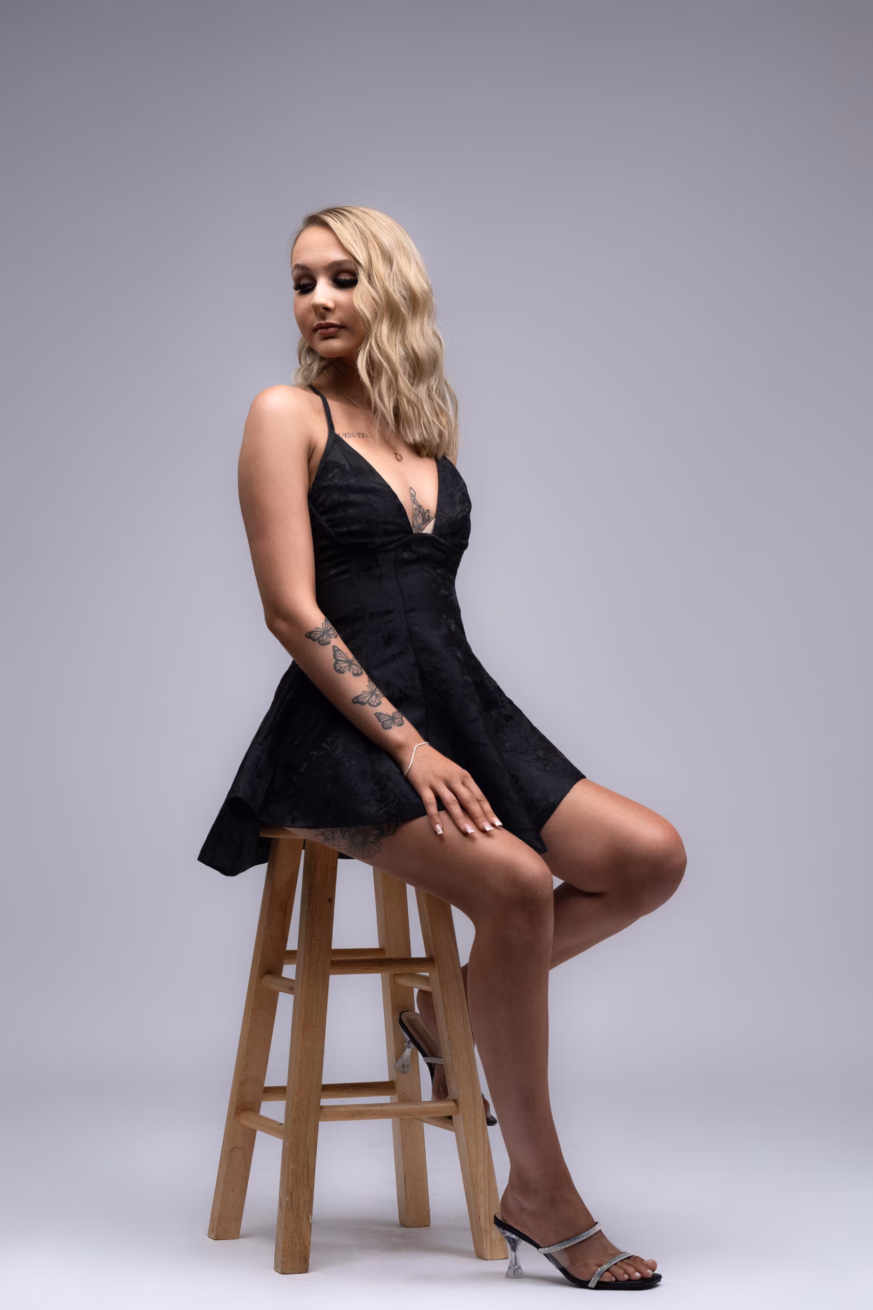 Woman in a black dress perched on a tall stool