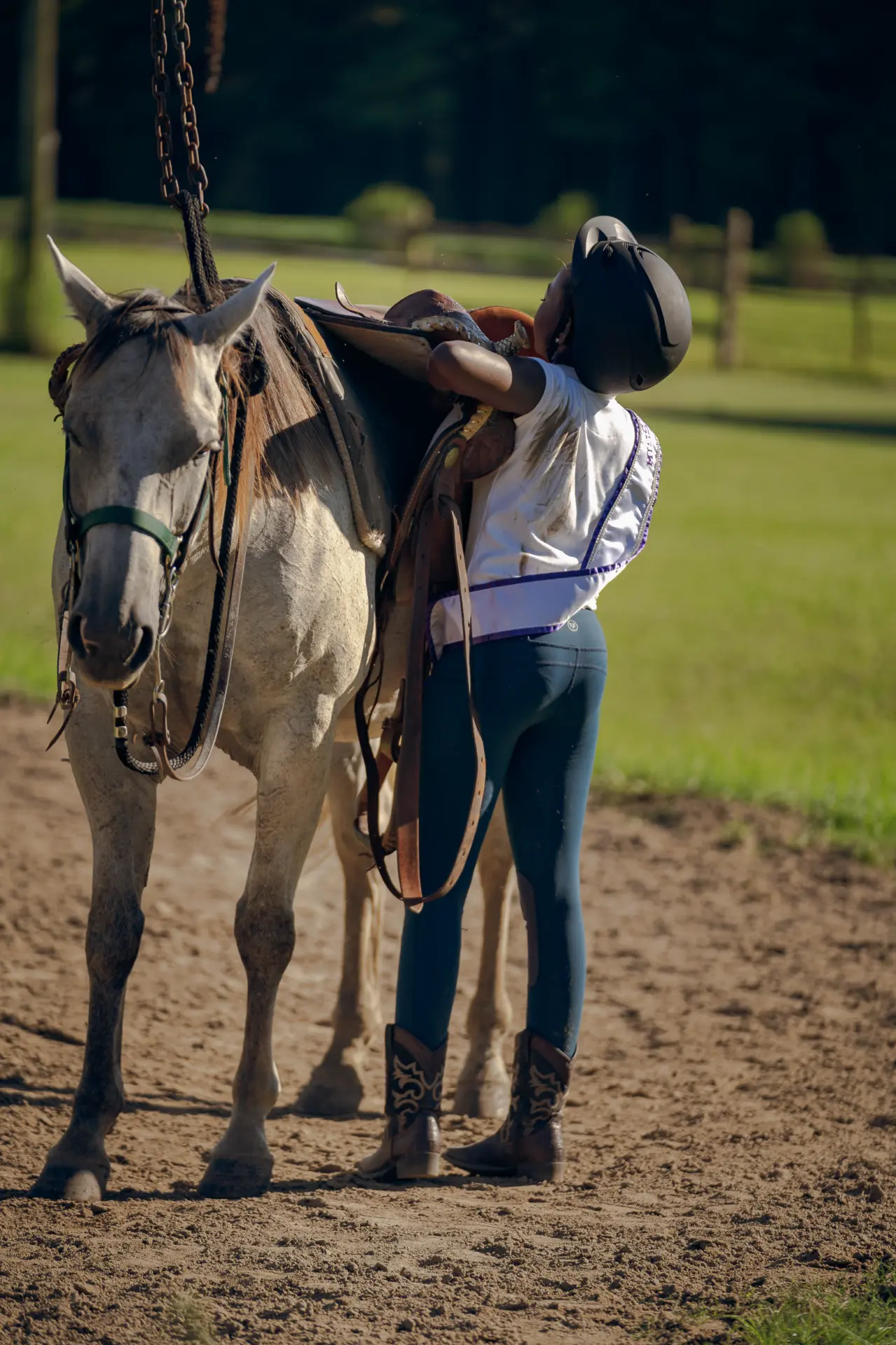 Woman standing with her horse on a farm at golden hour