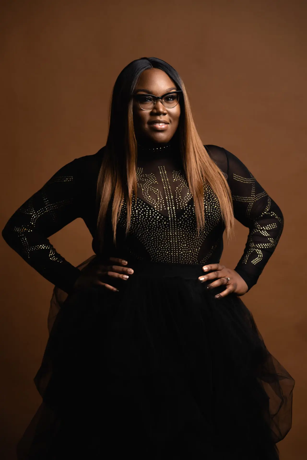 Woman in a sheer black gown against a brown backdrop