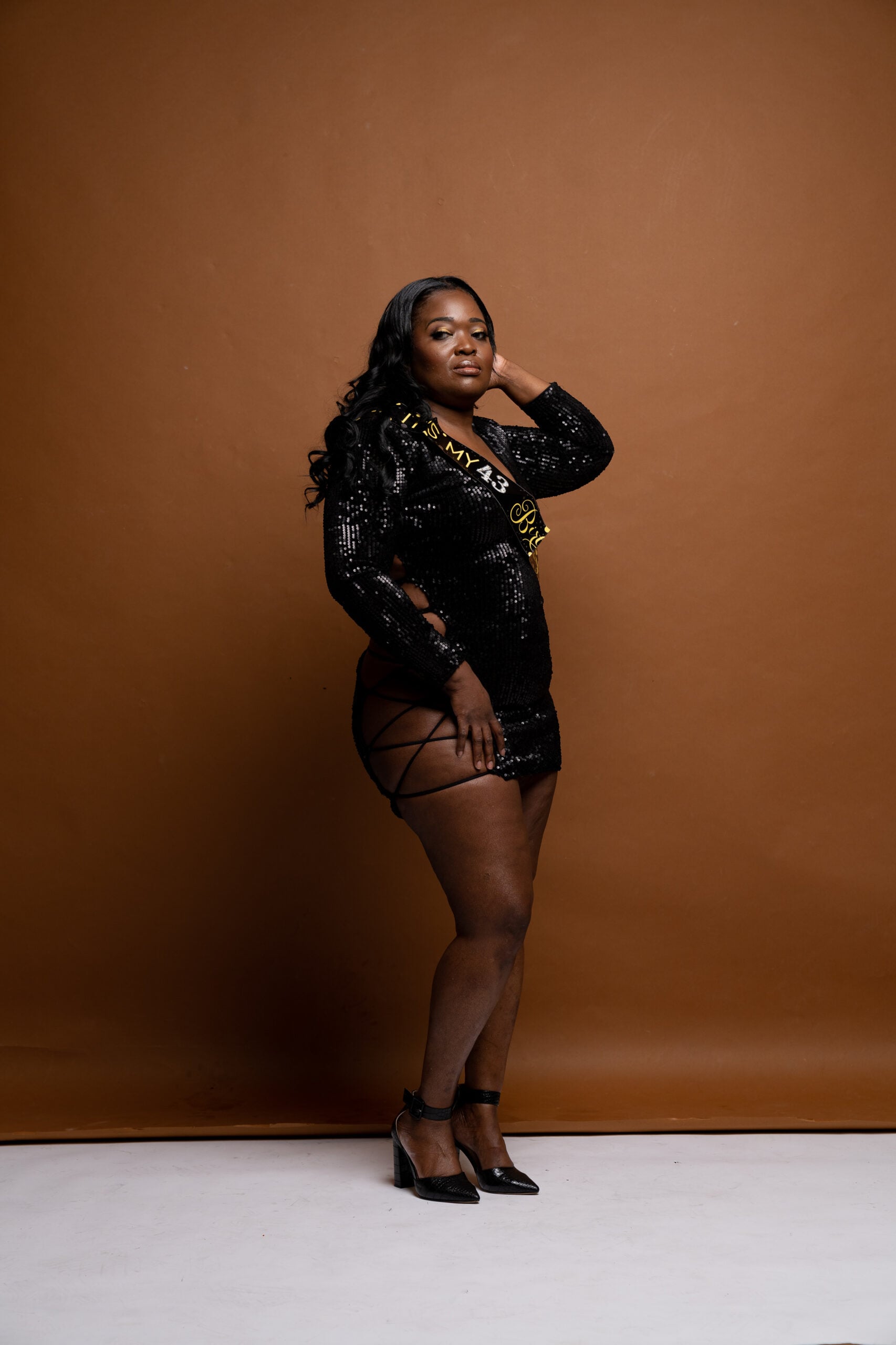Woman in black posing against a warm brown backdrop