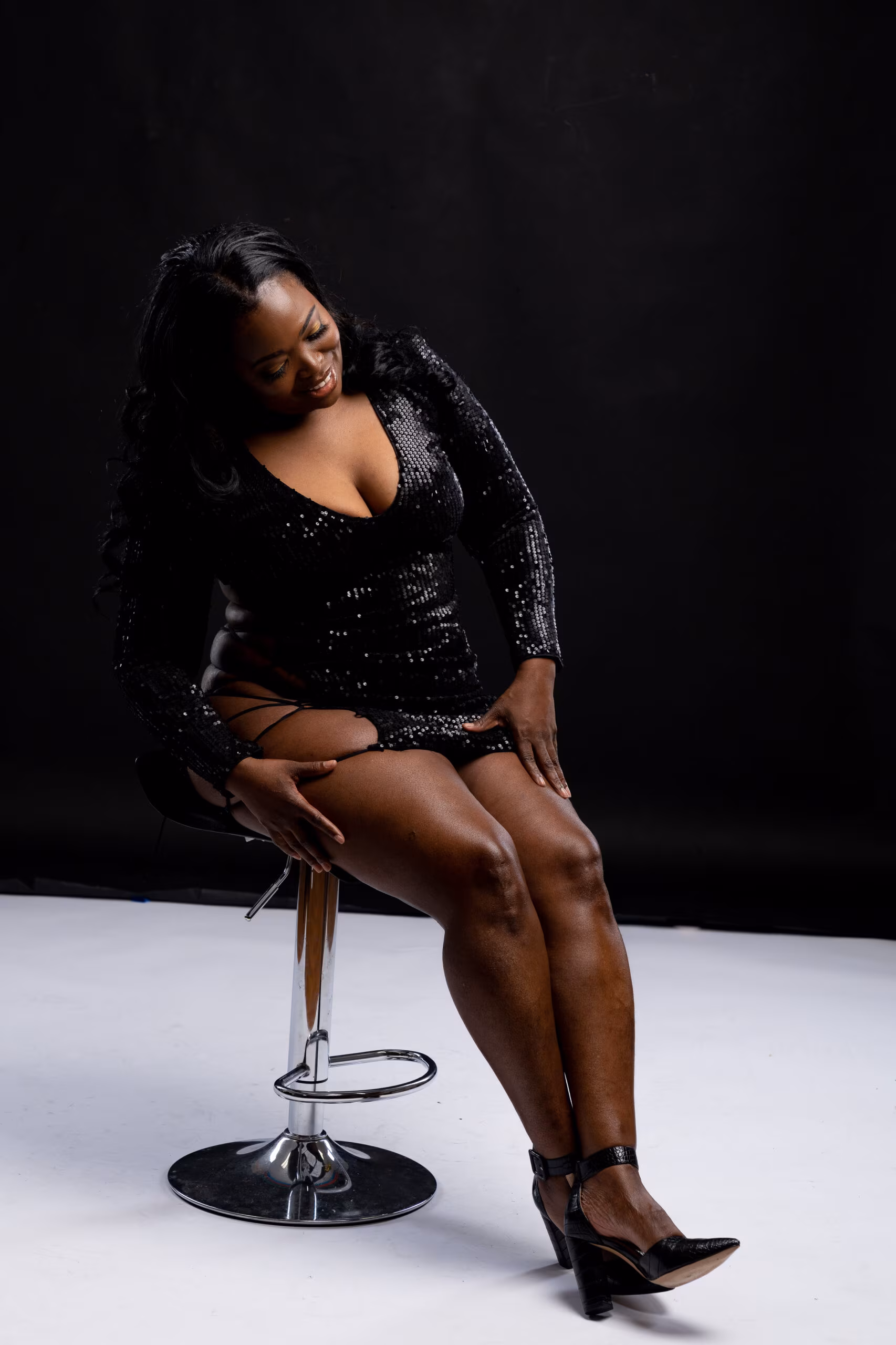 Woman in black seated on a stool for a birthday portrait