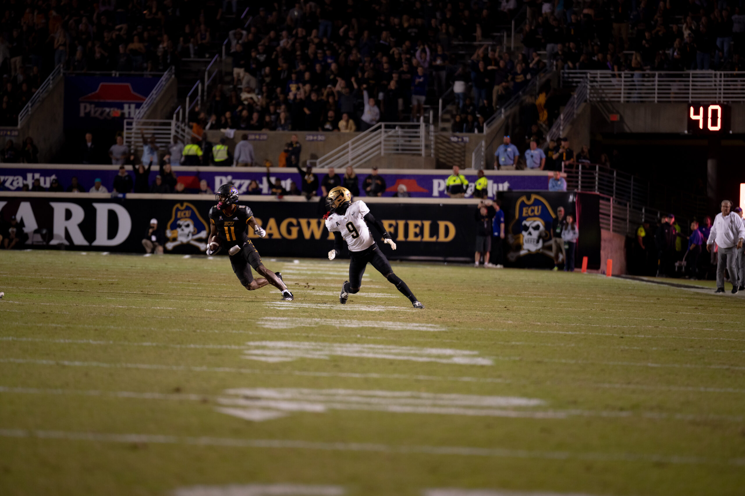 My First ECU College Football Photography Assignment 264 Players running a play past the Bagwell Field sign