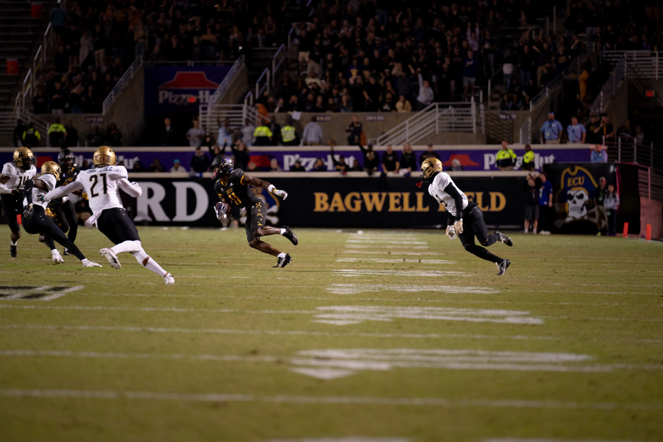 My First ECU College Football Photography Assignment 143 Players running a play in front of the Bagwell Field sign