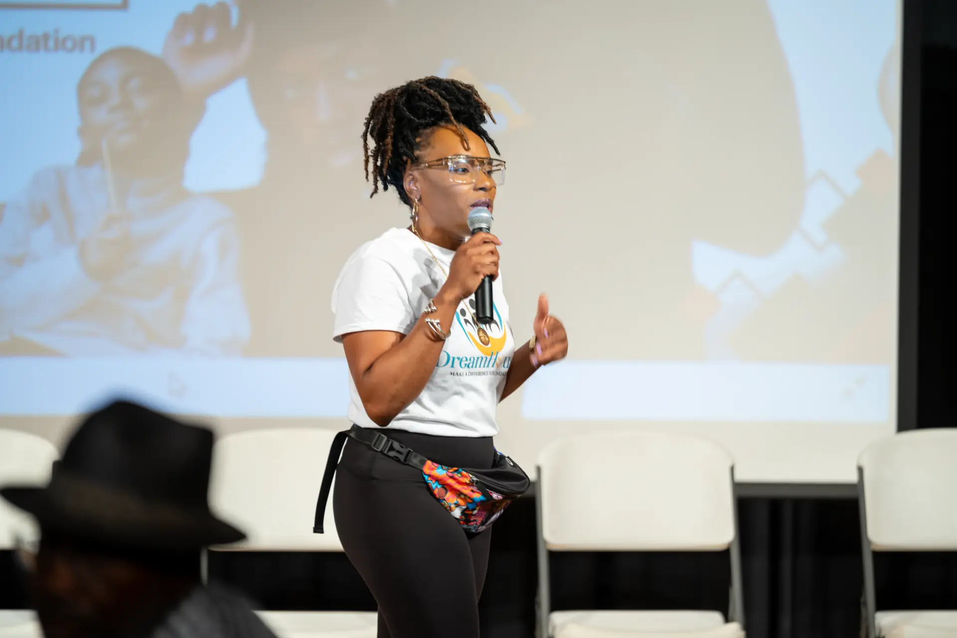 Presenter speaking into a microphone in front of a screen