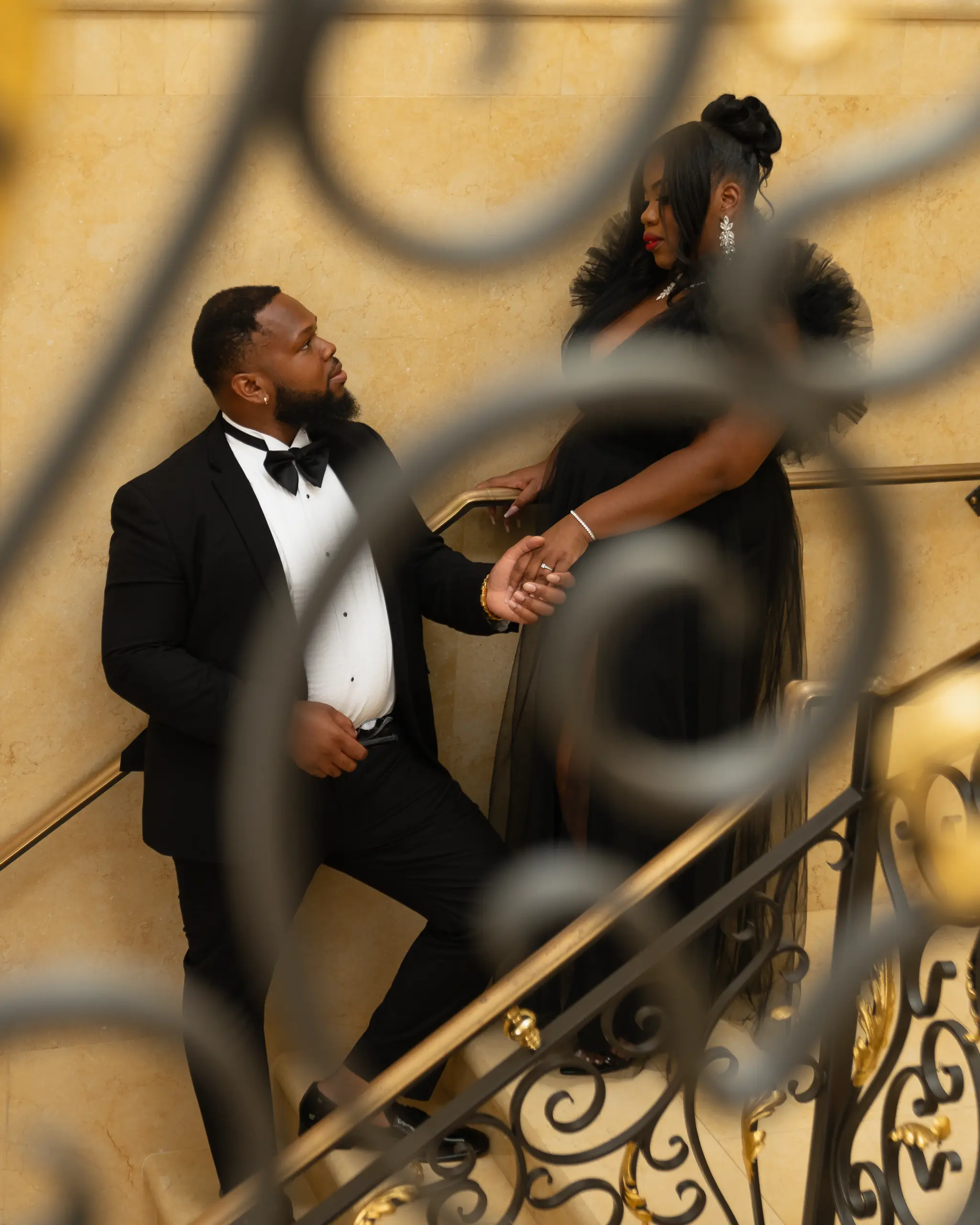 Couple poses on a grand staircase with an ornate iron railing
