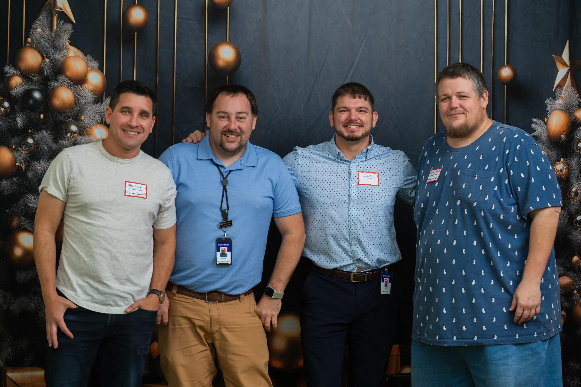 Men in blue shirts posing in a row at the holiday party