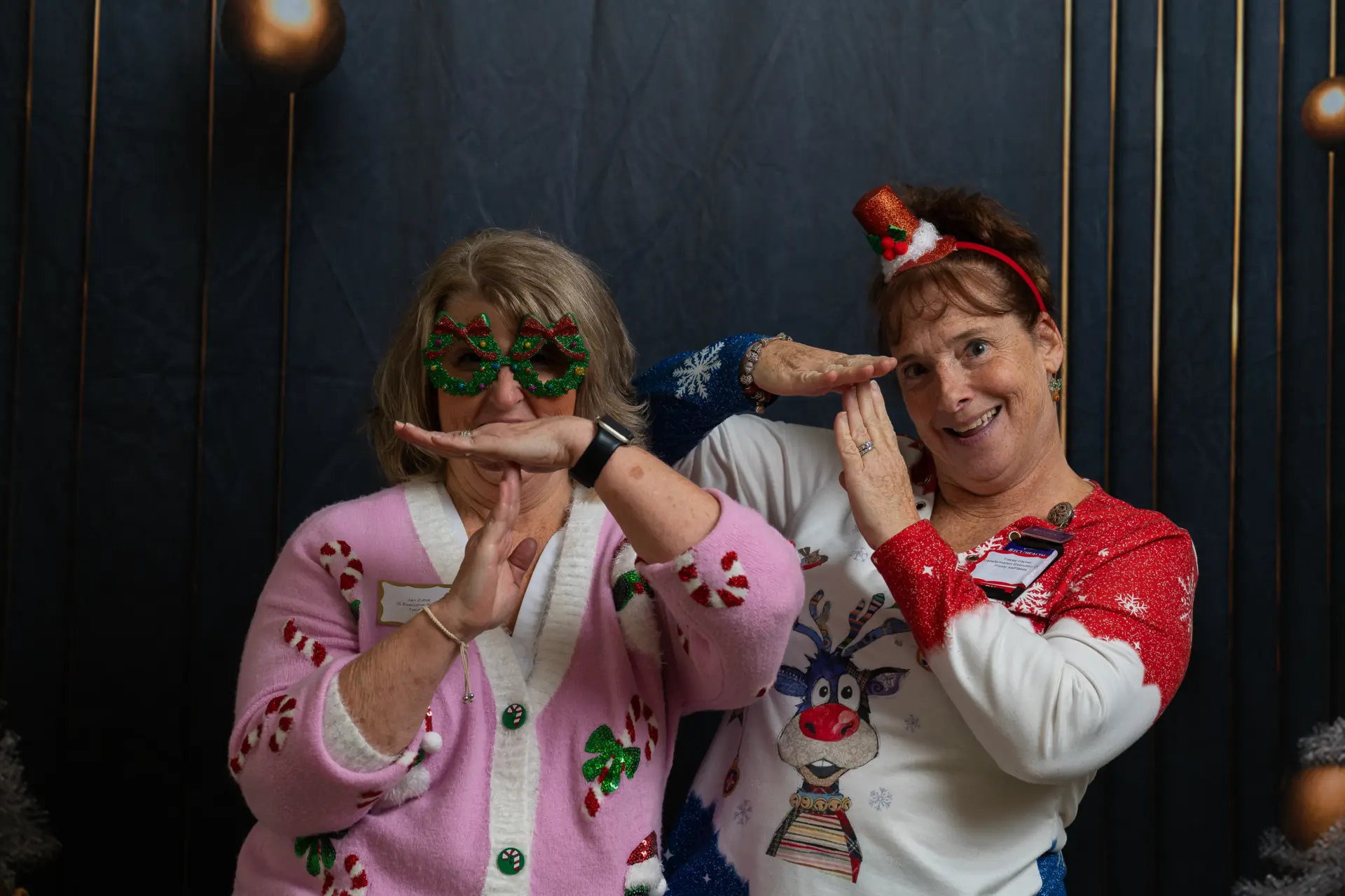 Two guests in festive glasses and hats clowning for the camera