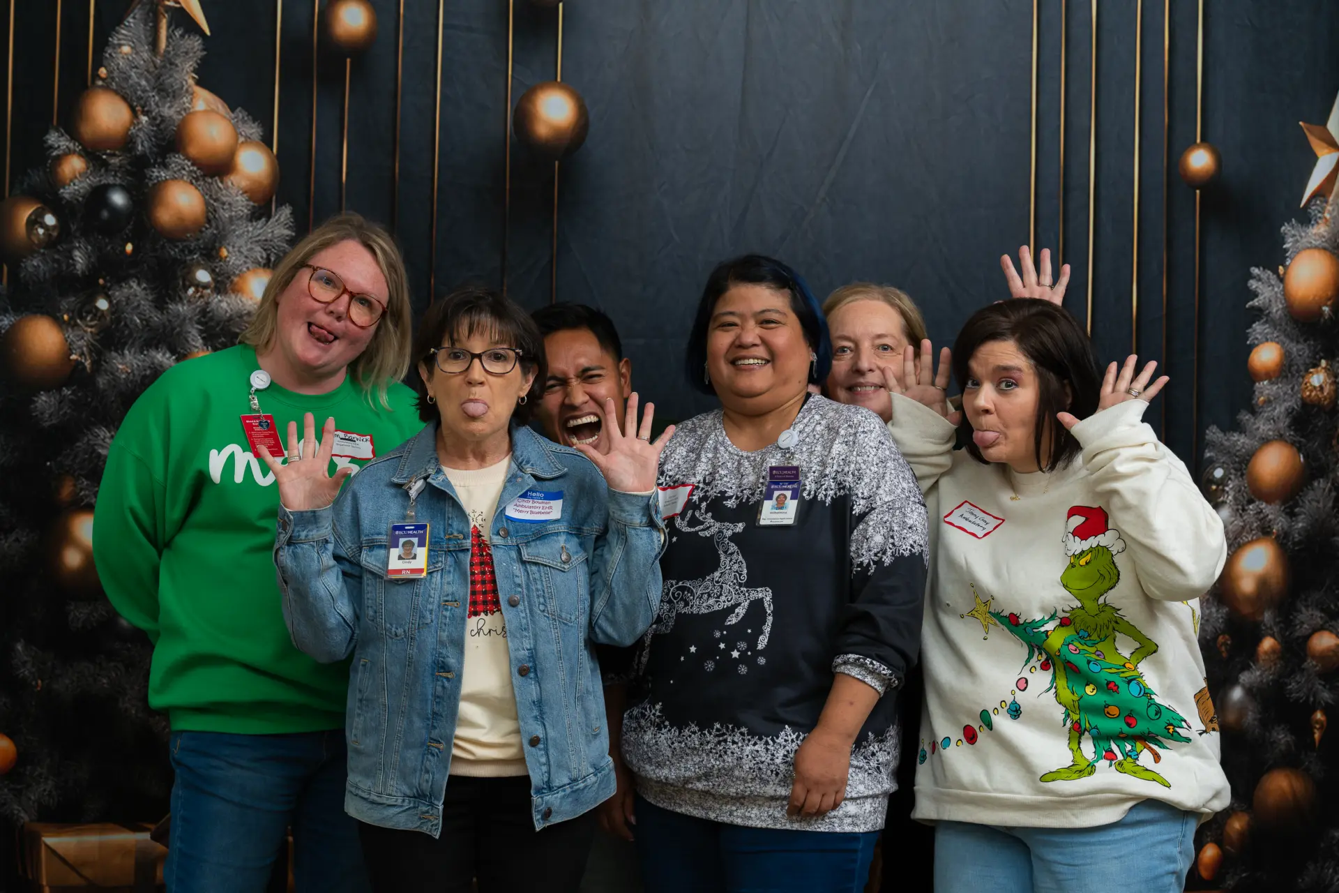Coworkers in ugly Christmas sweaters waving at the camera