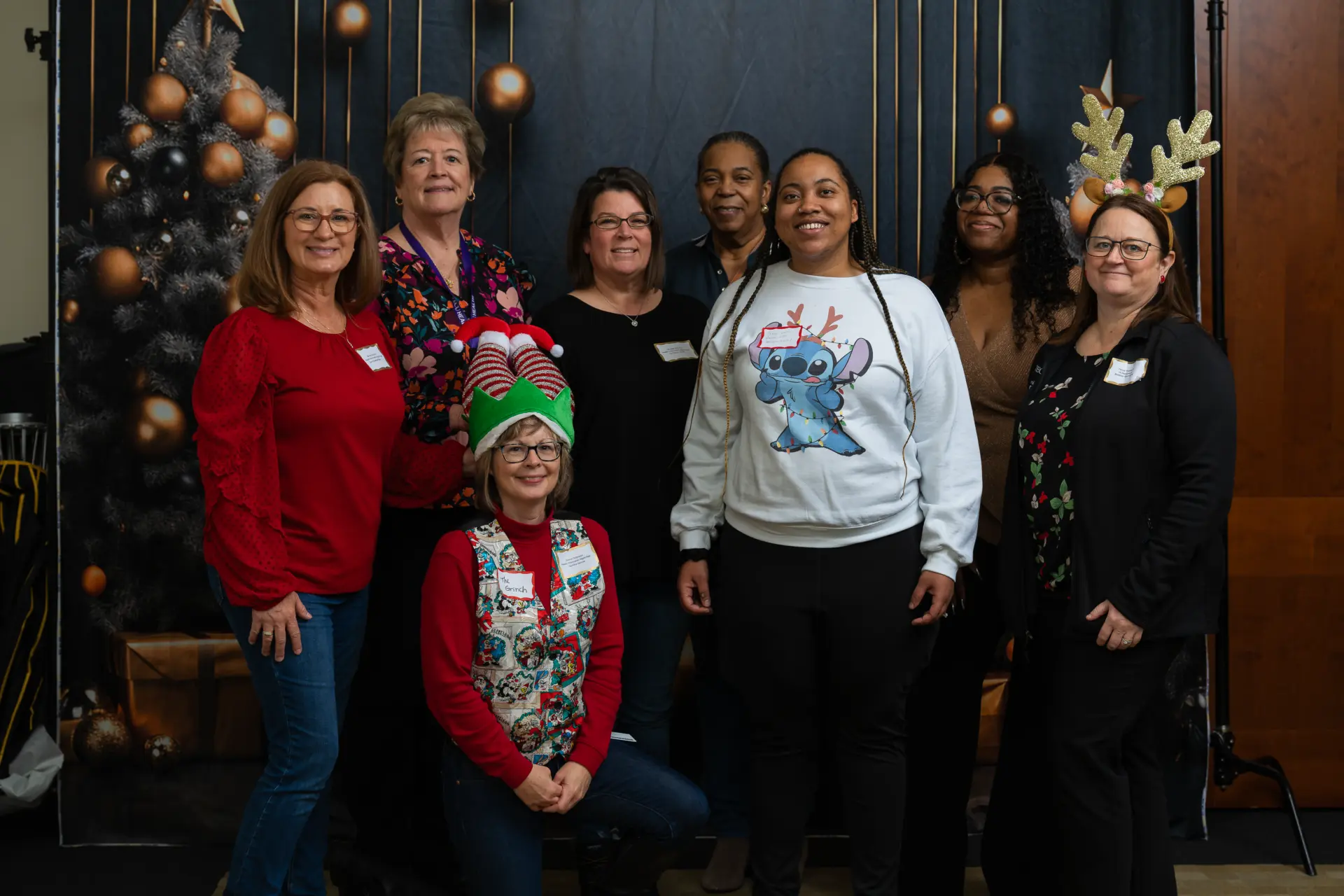 Coworkers in holiday attire lined up at the party backdrop