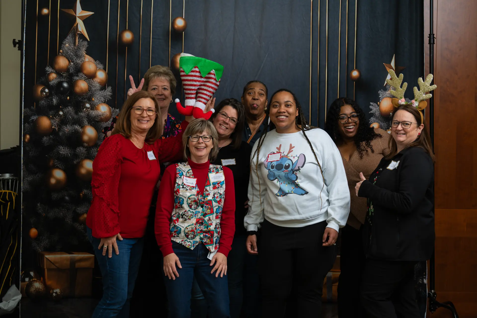 Team in elf hats and sweaters posing in front of the trees