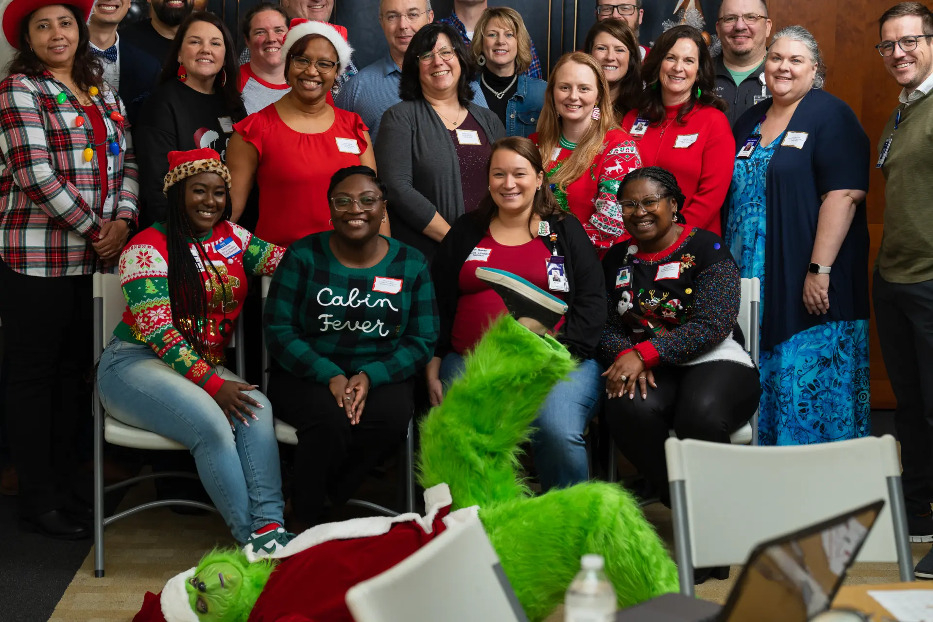Crowd of coworkers gathered with the Grinch for a holiday group shot