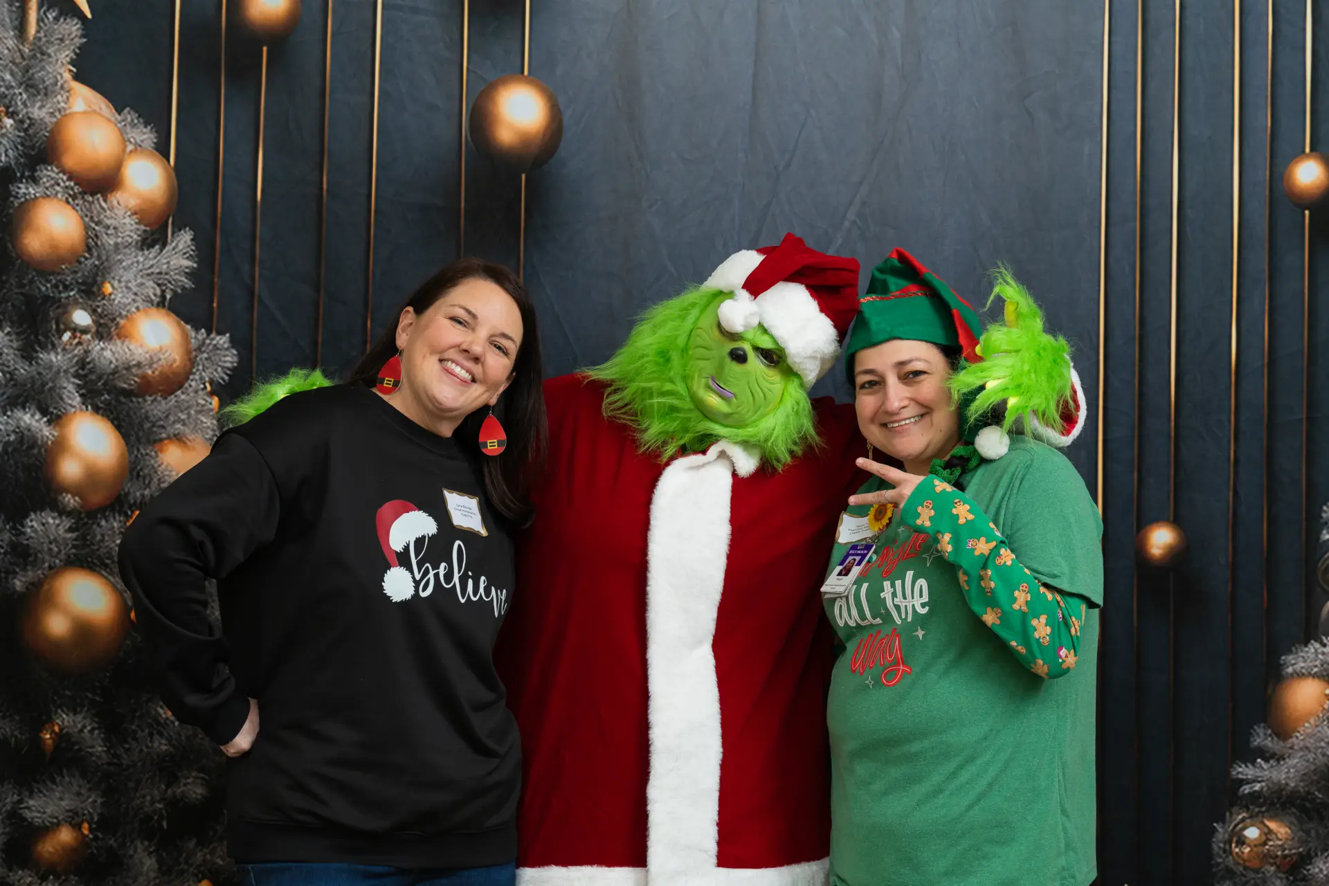 Guests hugging the Grinch character in front of the Christmas trees