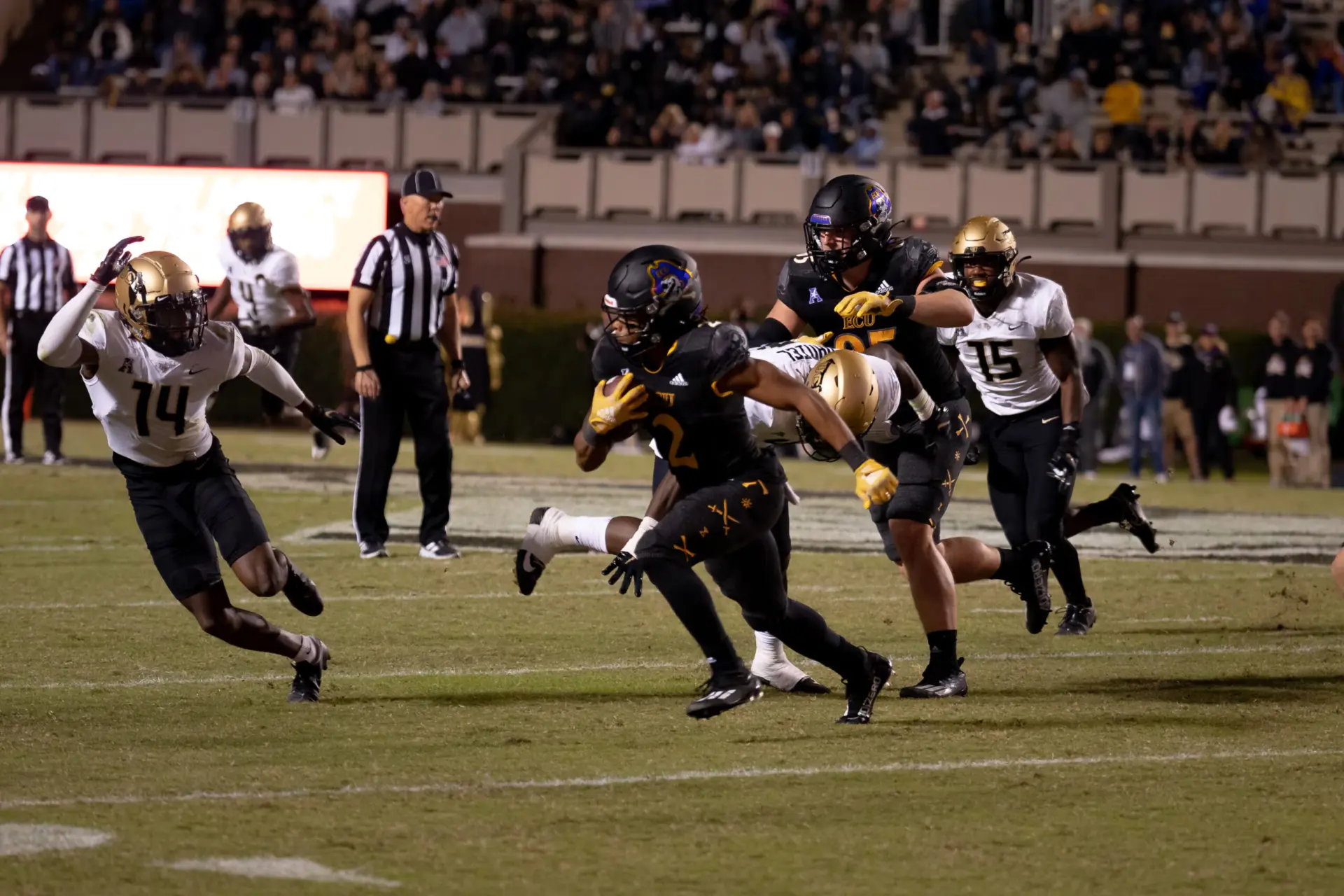 ECU players running a play under the stadium lights