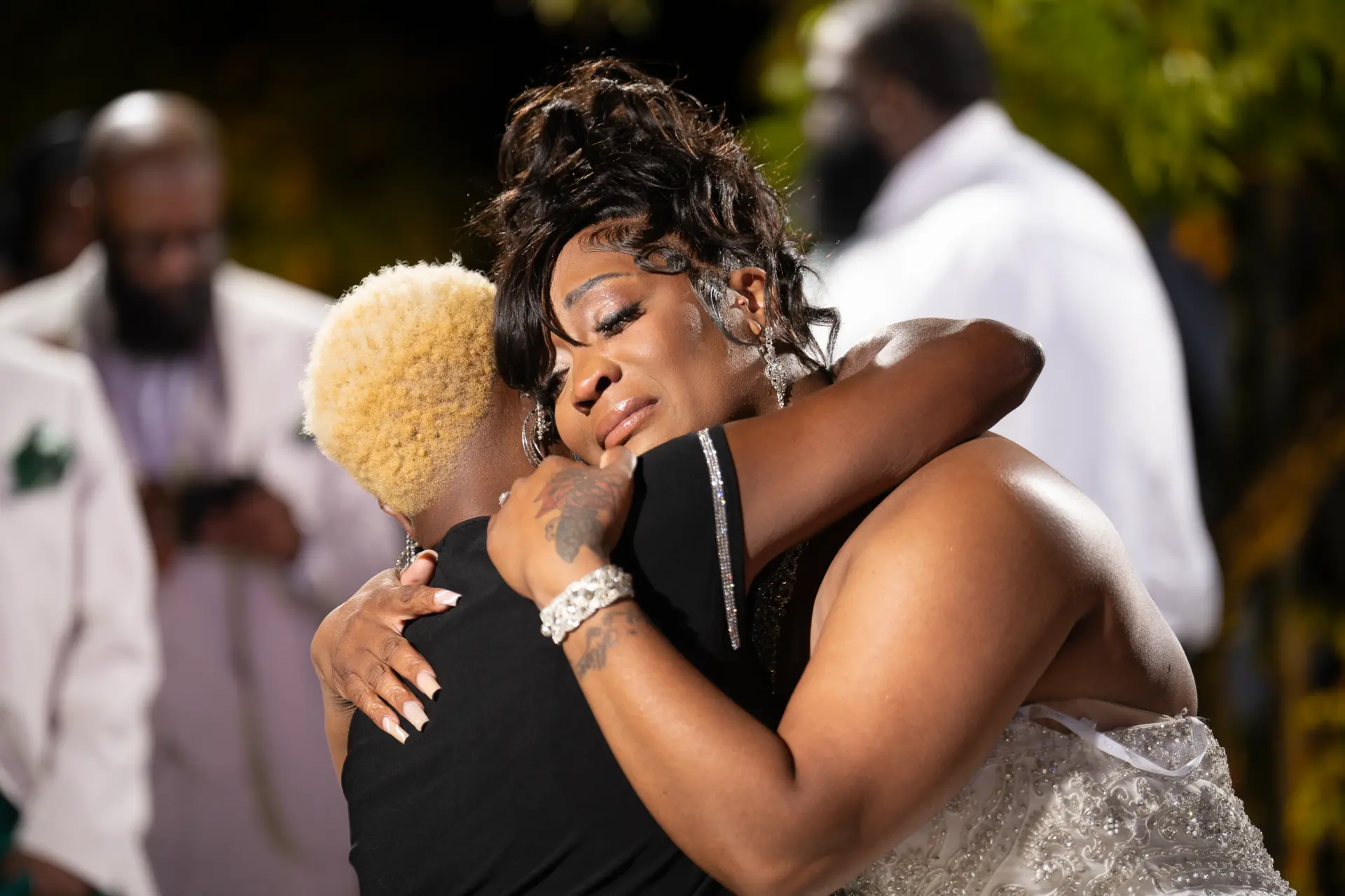 Bride sharing a tearful hug with a loved one at the reception