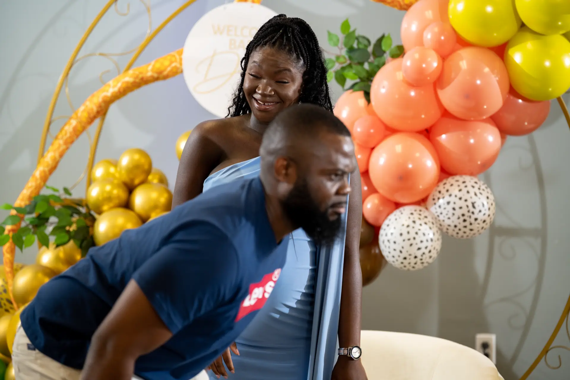 Couple celebrating in front of an orange and peach balloon garland