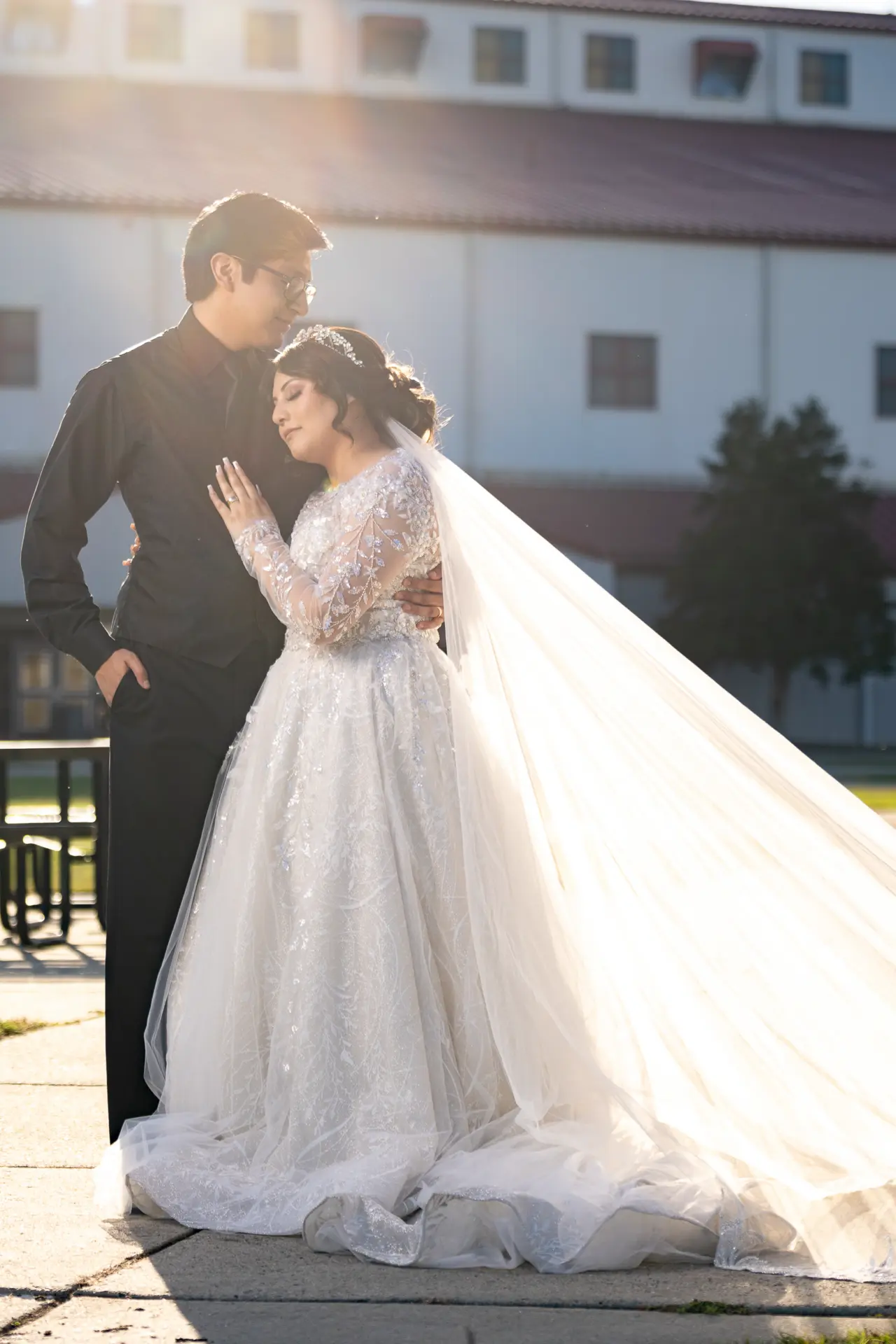 Bride's cathedral veil sweeping across the lawn as the groom holds her close