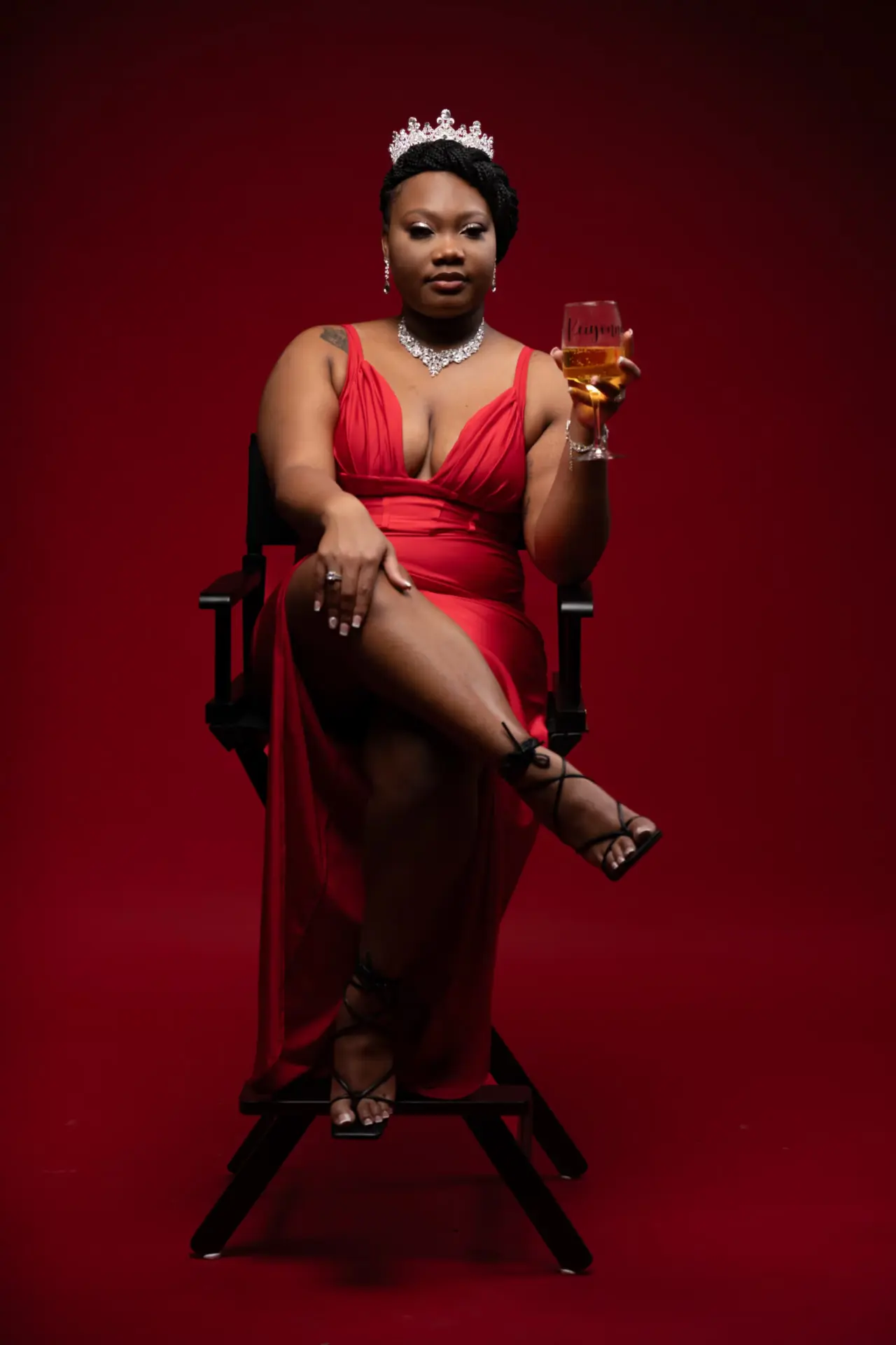 Woman in a red dress and crown seated in a red throne chair