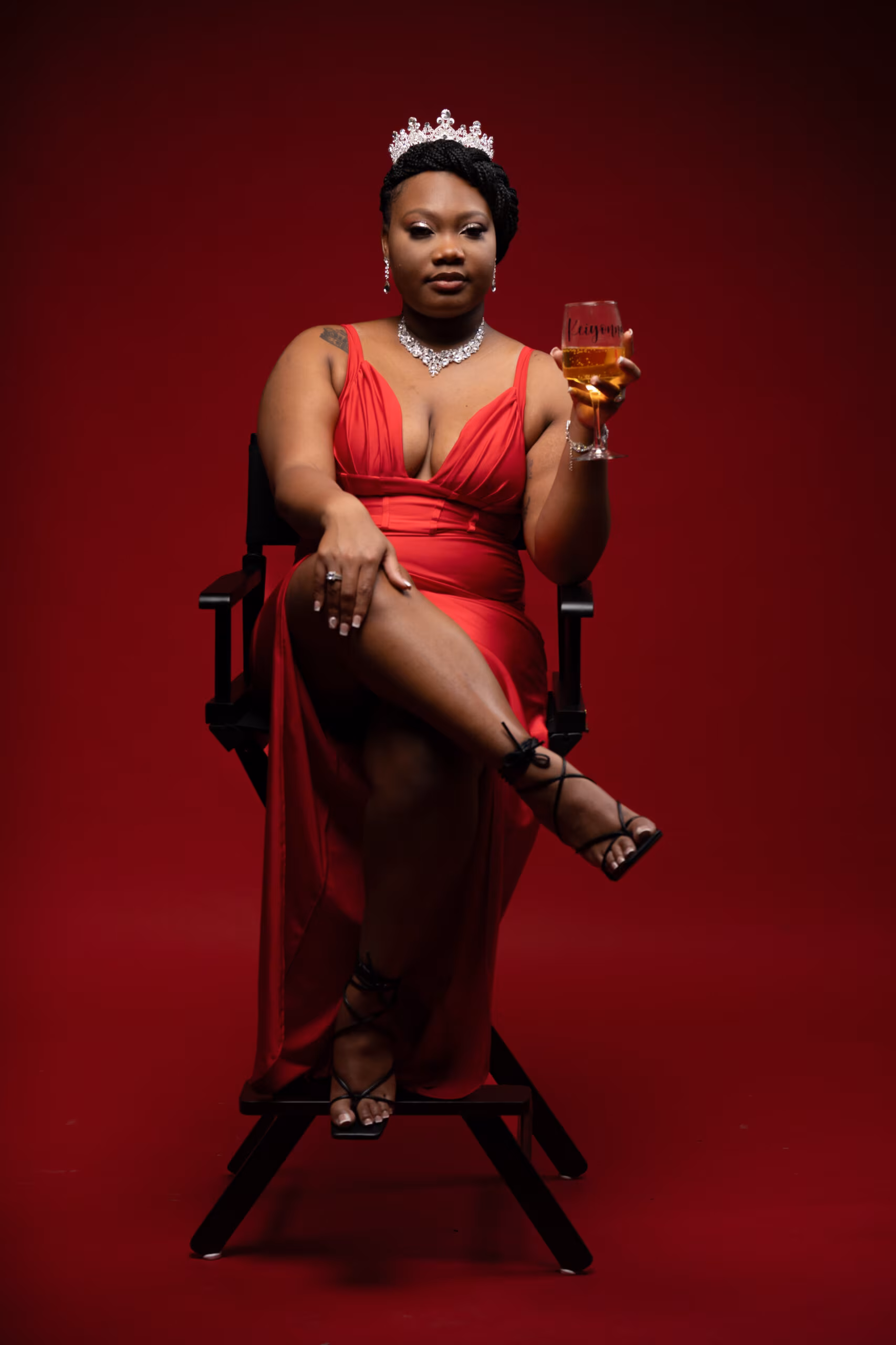 Woman in a red dress and crown seated in a red throne chair