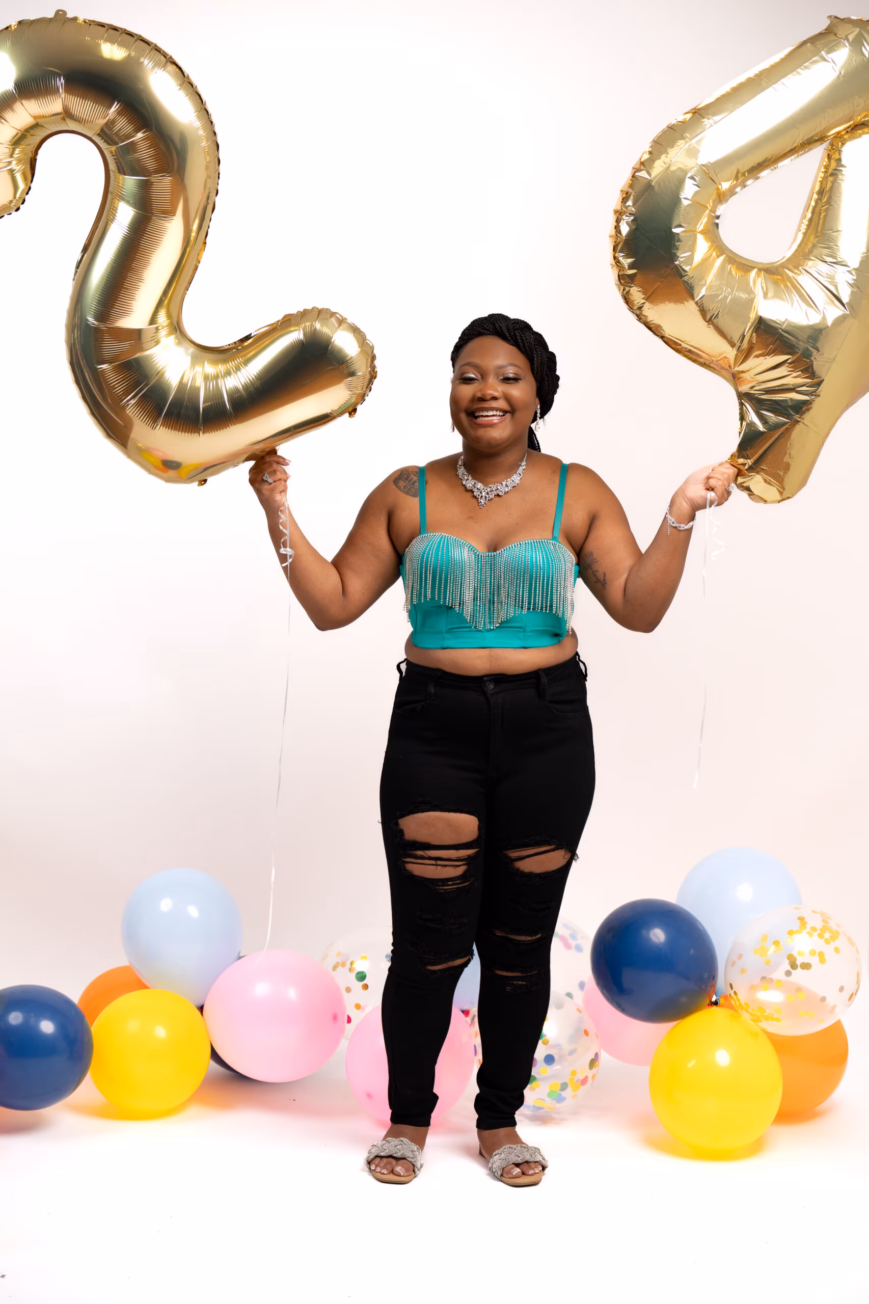 Woman in teal between gold "24" balloons