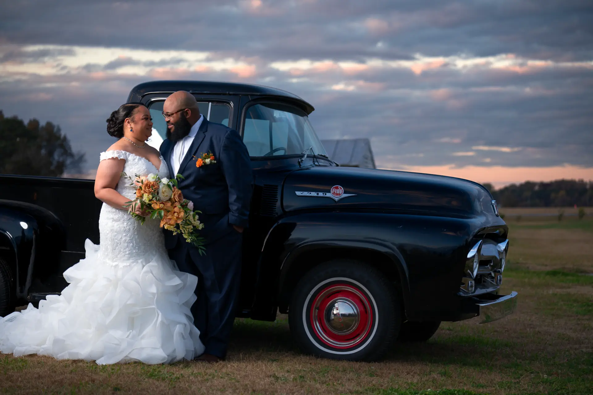 Bride and groom with bouquet beside a vintage black truck