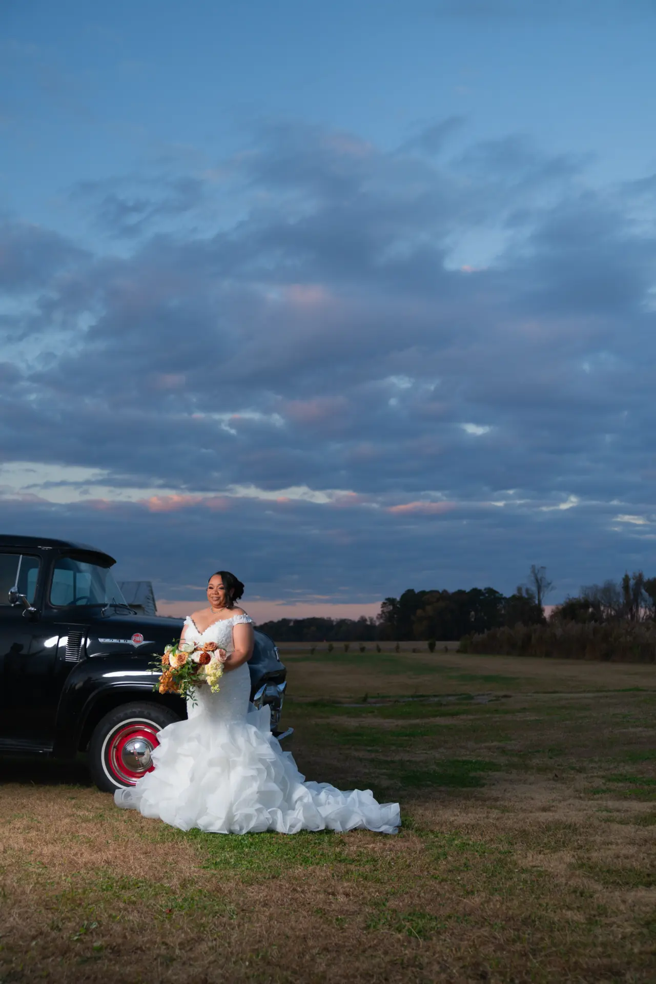 Bride and groom beside a vintage truck at dusk