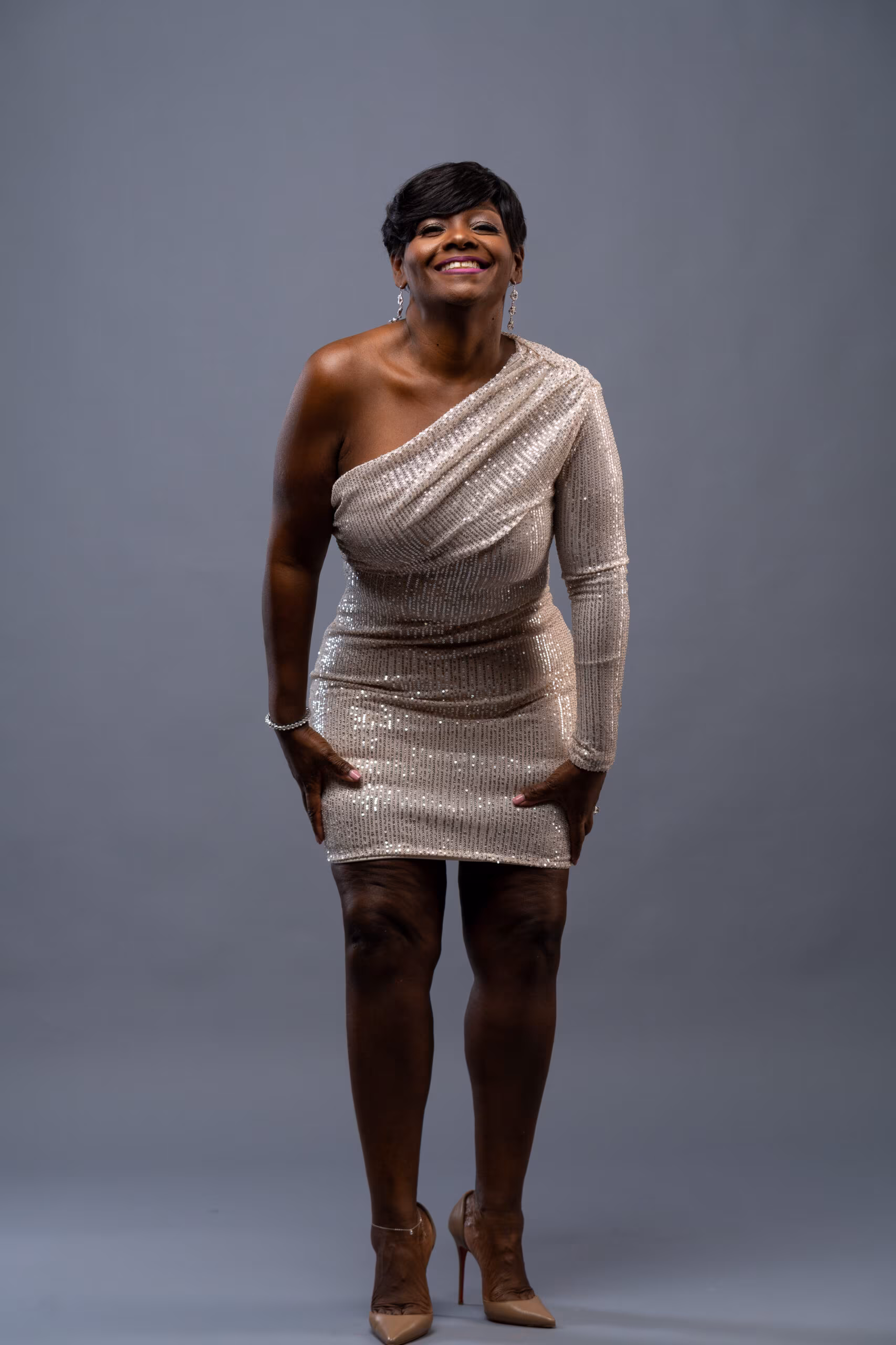 Woman in a silver dress posing on gray