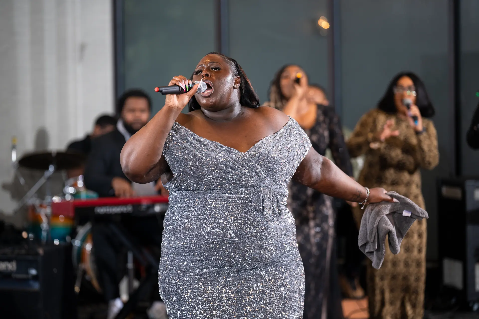 Singer in a silver dress performing for a seated audience