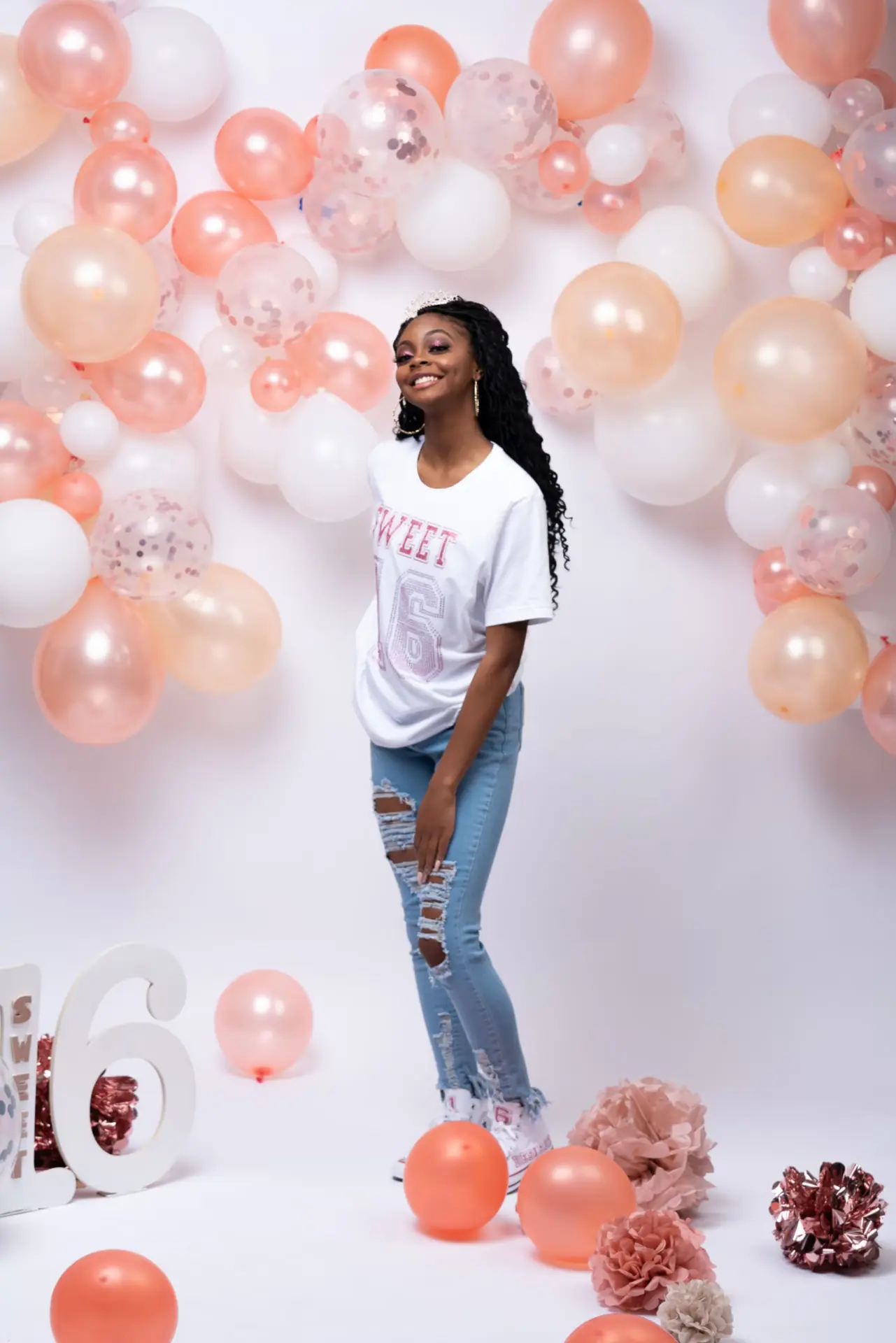 Woman in white surrounded by peach and white balloons