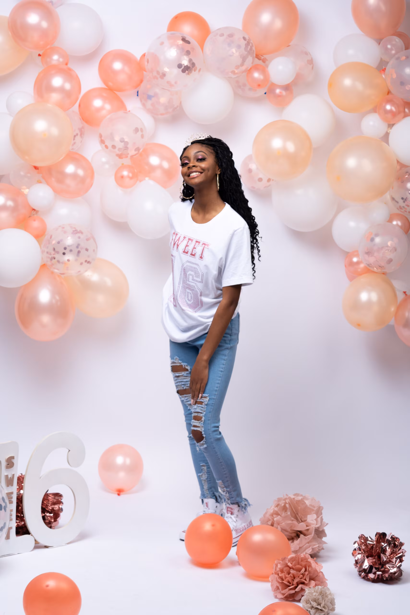 Woman in white surrounded by peach and white balloons