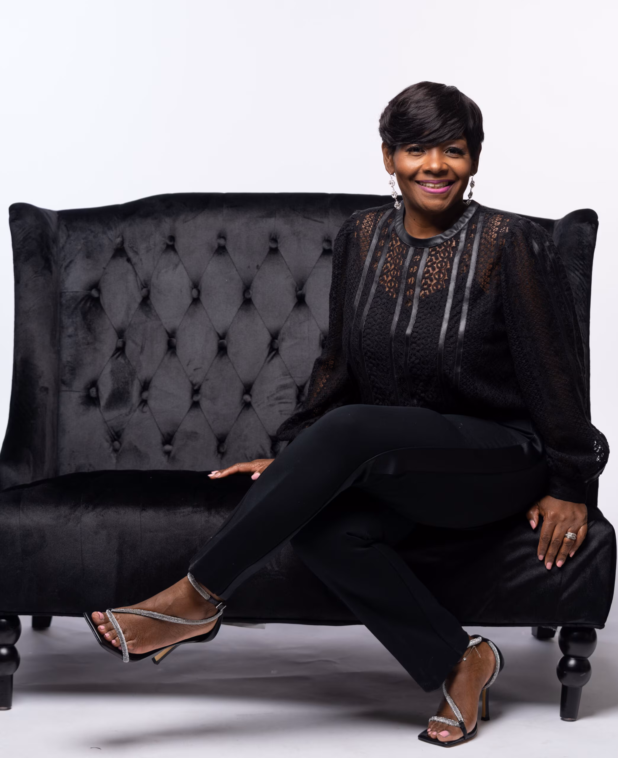 Woman in black lounging on a tufted black sofa
