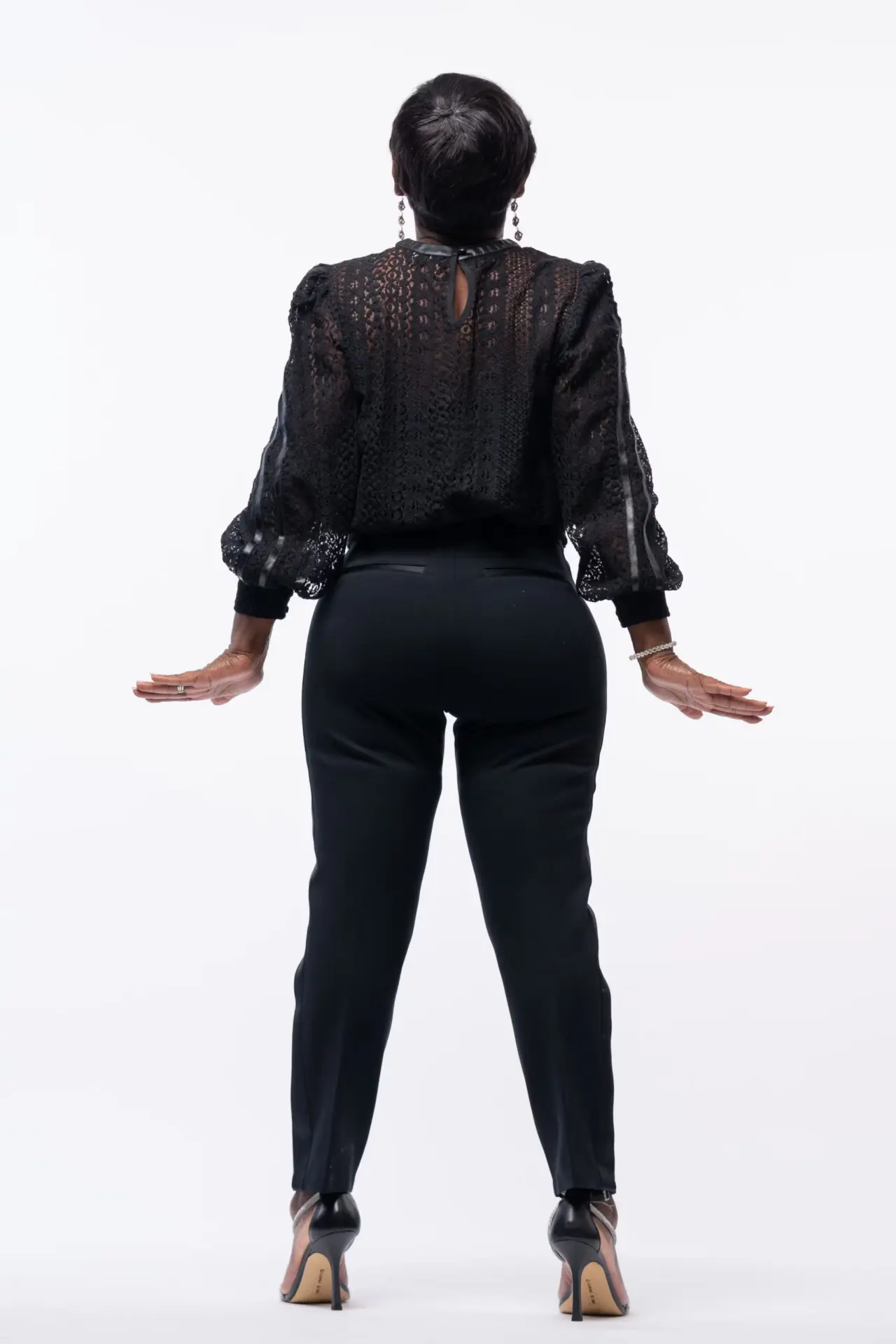 Woman in a black outfit posing with arms out on white