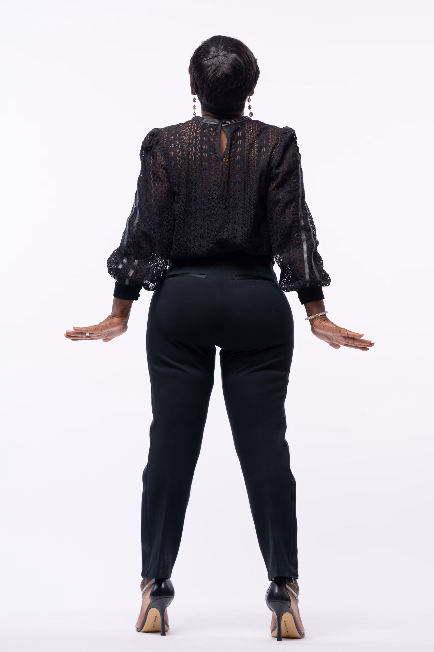 Woman in a black outfit posing with arms out on white