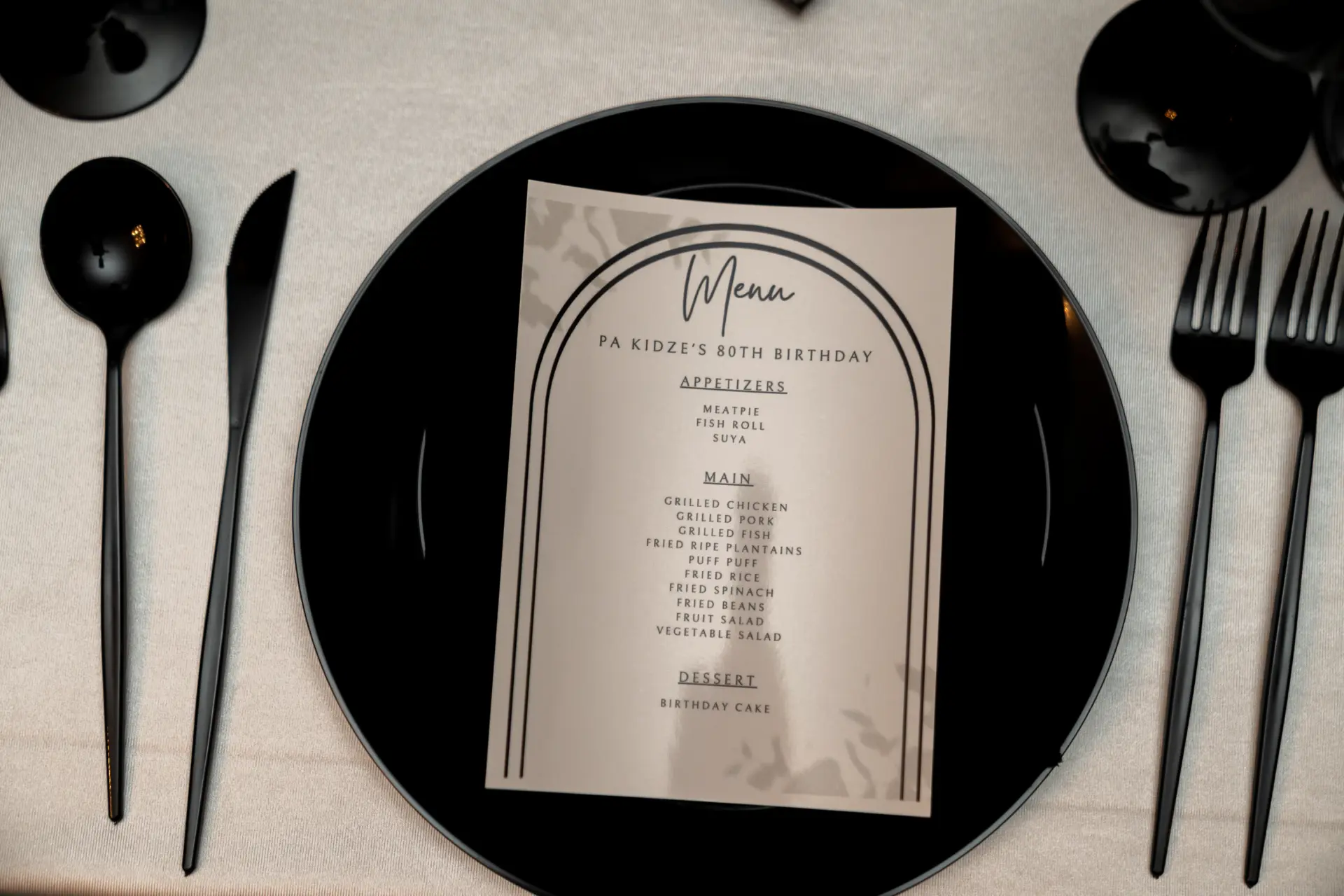 Black tablescape with a menu card on a charger and black flatware