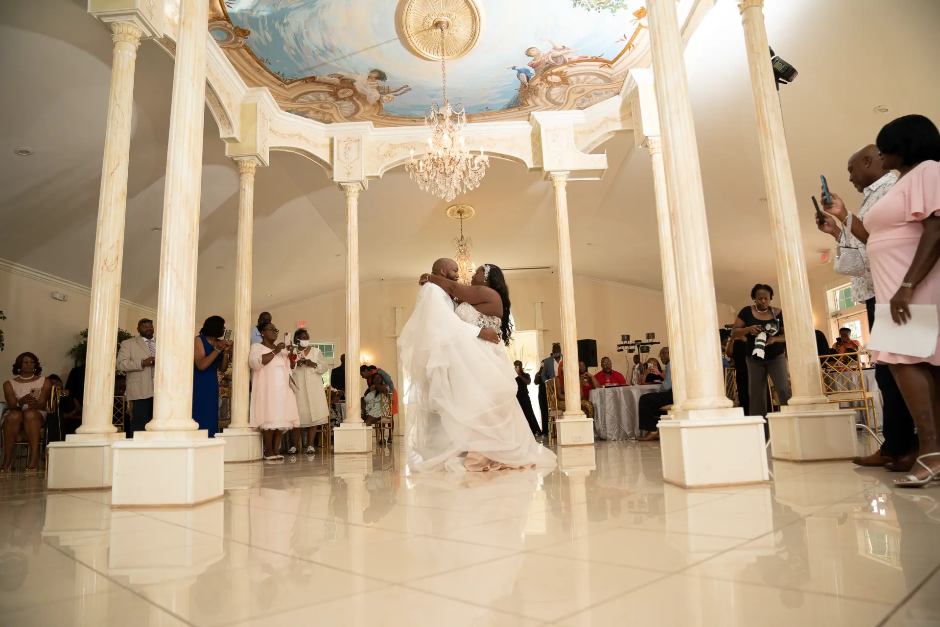 Wide view of an ornate reception hall with a domed gazebo and guests mingling