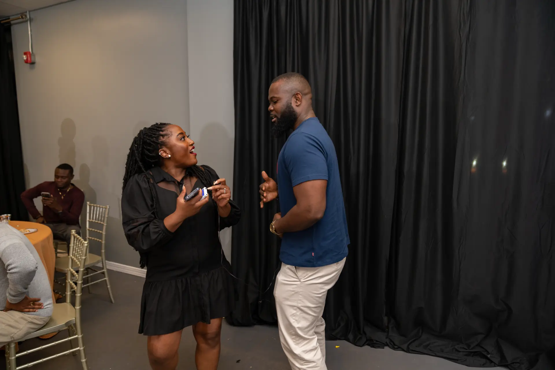 Couple chatting beside black drapery at a party