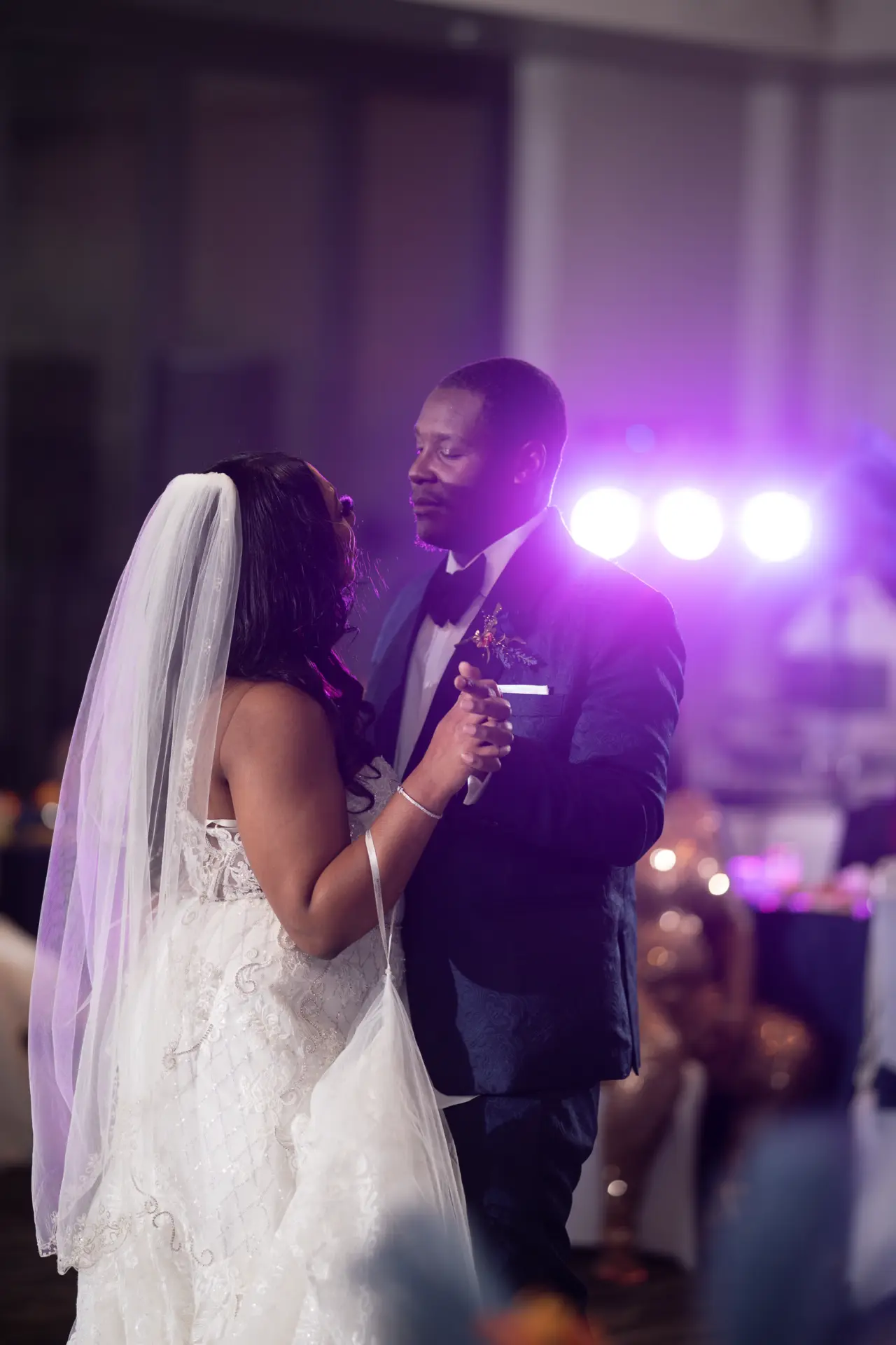 Couple dances under colorful reception lights