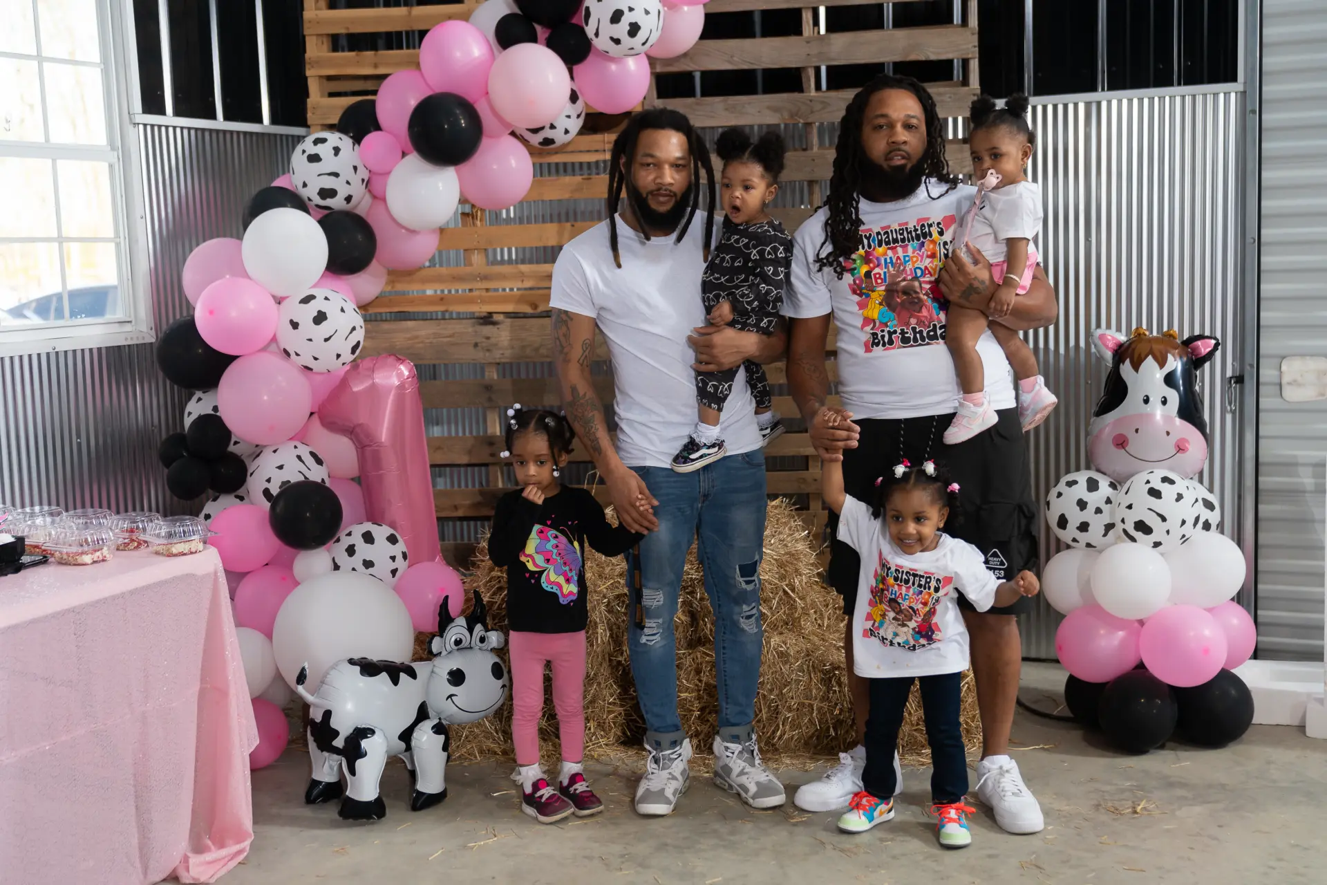 Family posing beside a pink balloon garland at a child's party