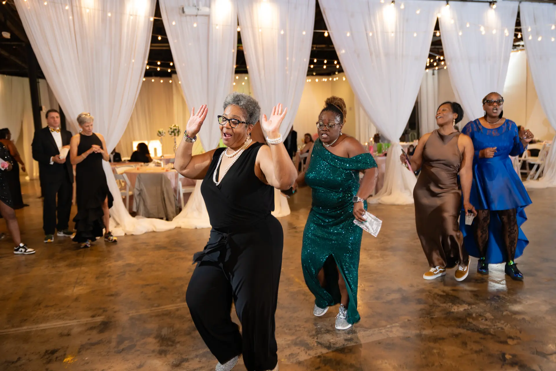 Women in colorful gowns dancing at an evening celebration