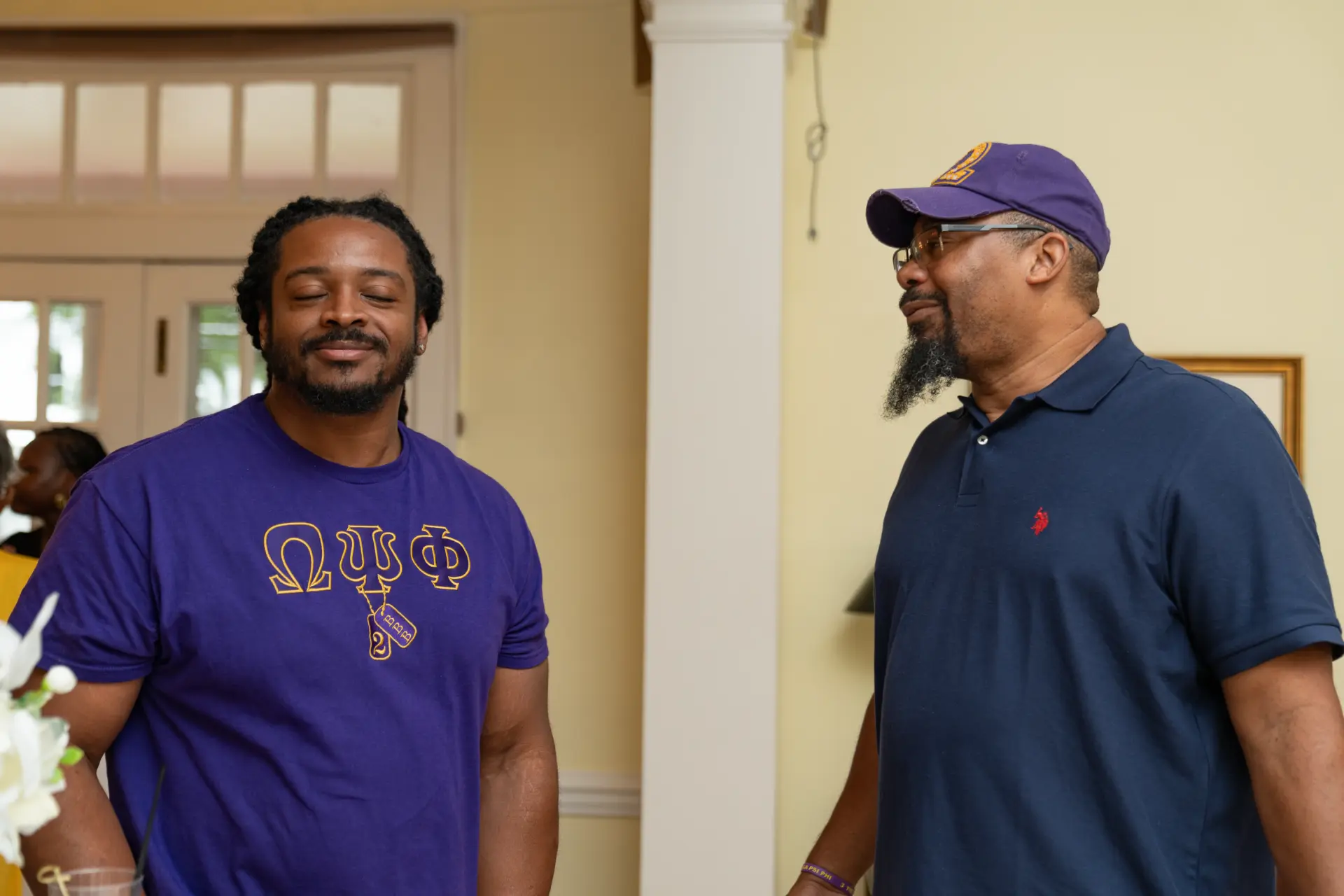 Two men in purple and navy chatting at a family celebration