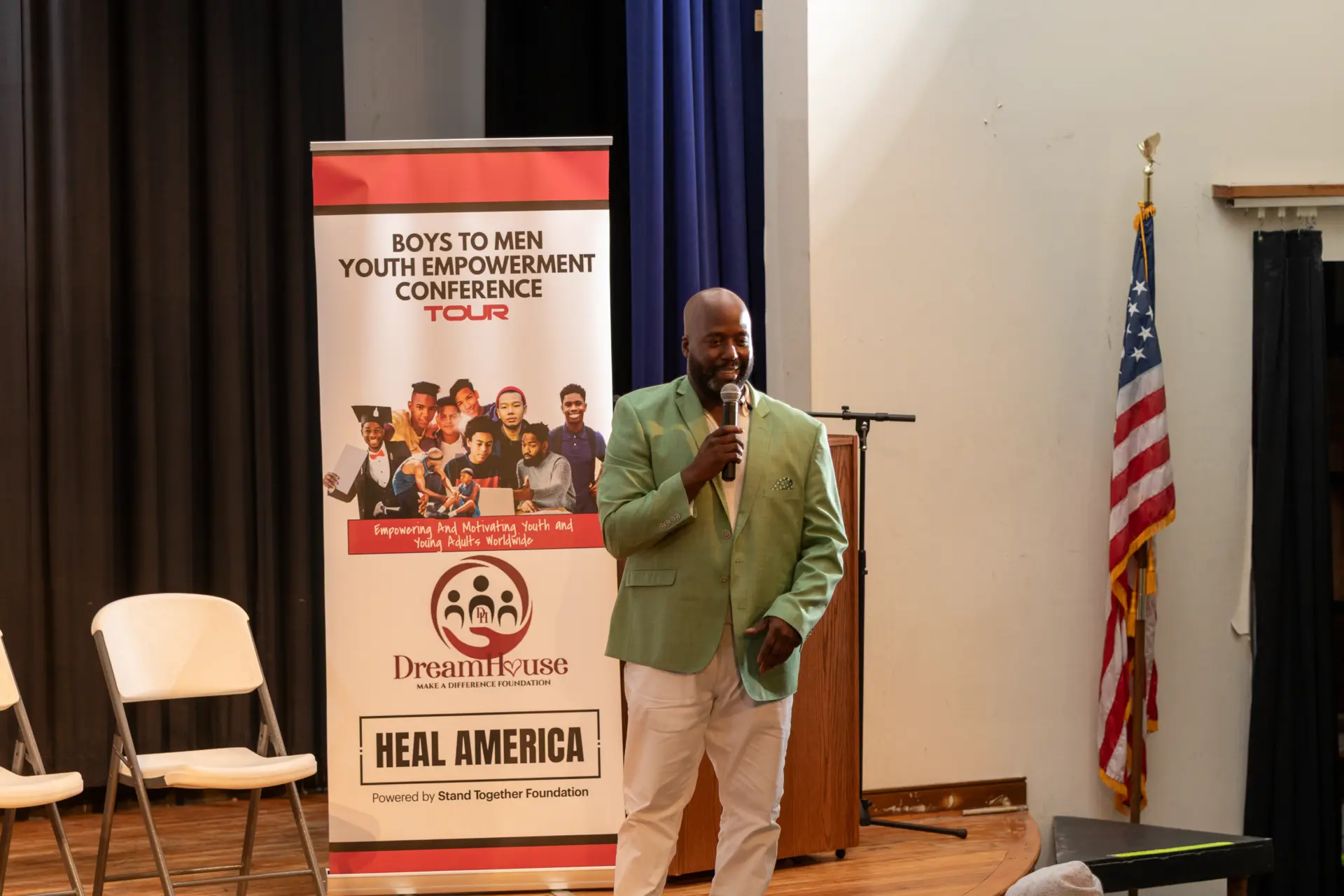 Speaker at a podium beside event banners and an American flag