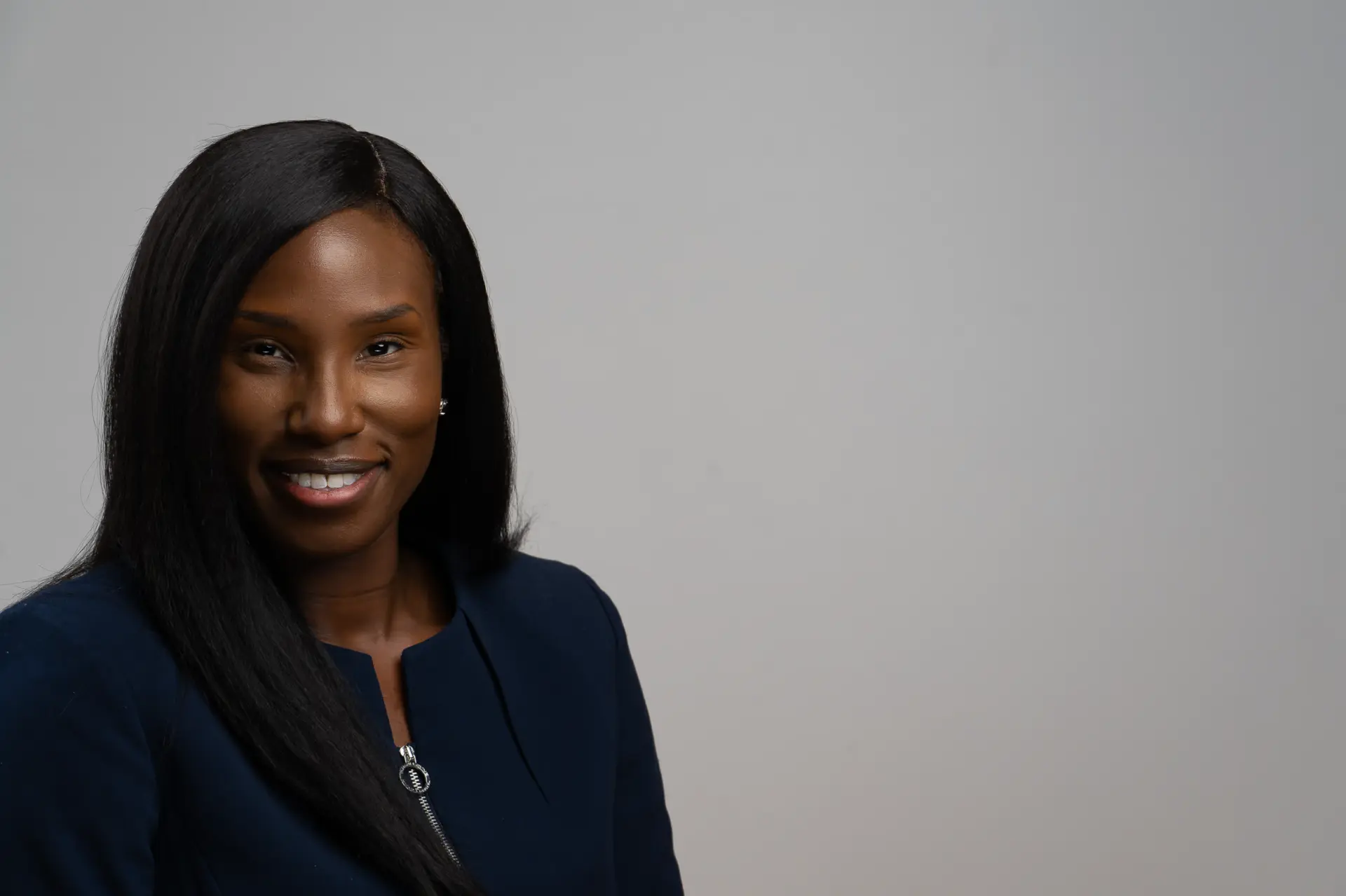 Woman in a navy top, professional headshot on light gray